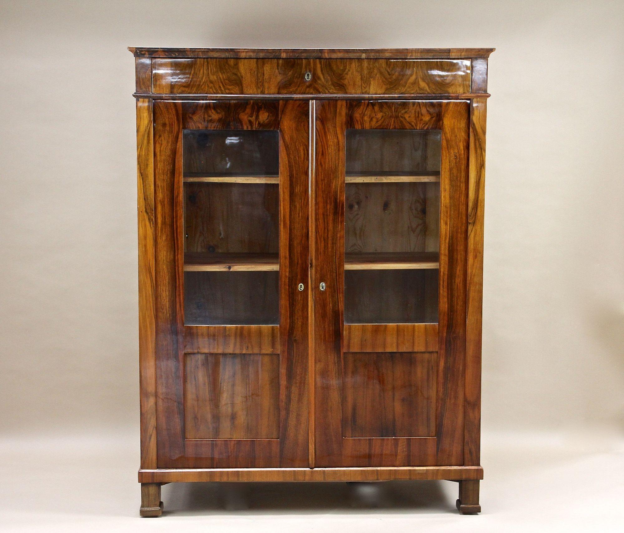 Remarkable 19th century Biedermeier walnut cabinet/ bookcase/ vitrine coming from the early period in Austria around 1835. Elaborately veneered in finest burr walnut the glossy surface shows an absolutel amazing grain. The front of this exceptional