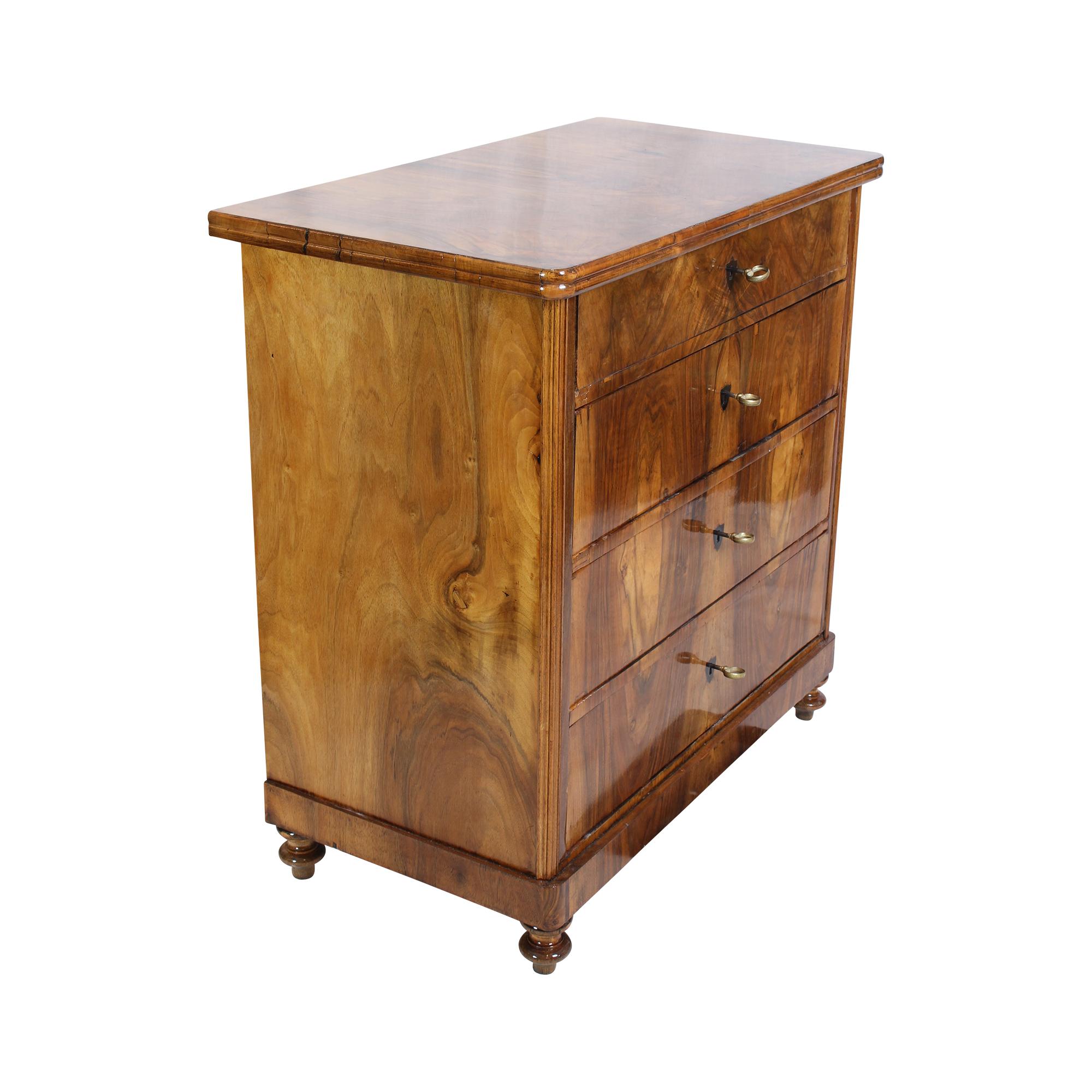 Beautiful narrow/not so large Biedermeier chest of drawers from around 1830. The chest of drawers has four drawers and a very beautiful walnut veneer. The chest of drawers comes from Mainz from the manufactory of Franz Xaver Riffel, as can be seen