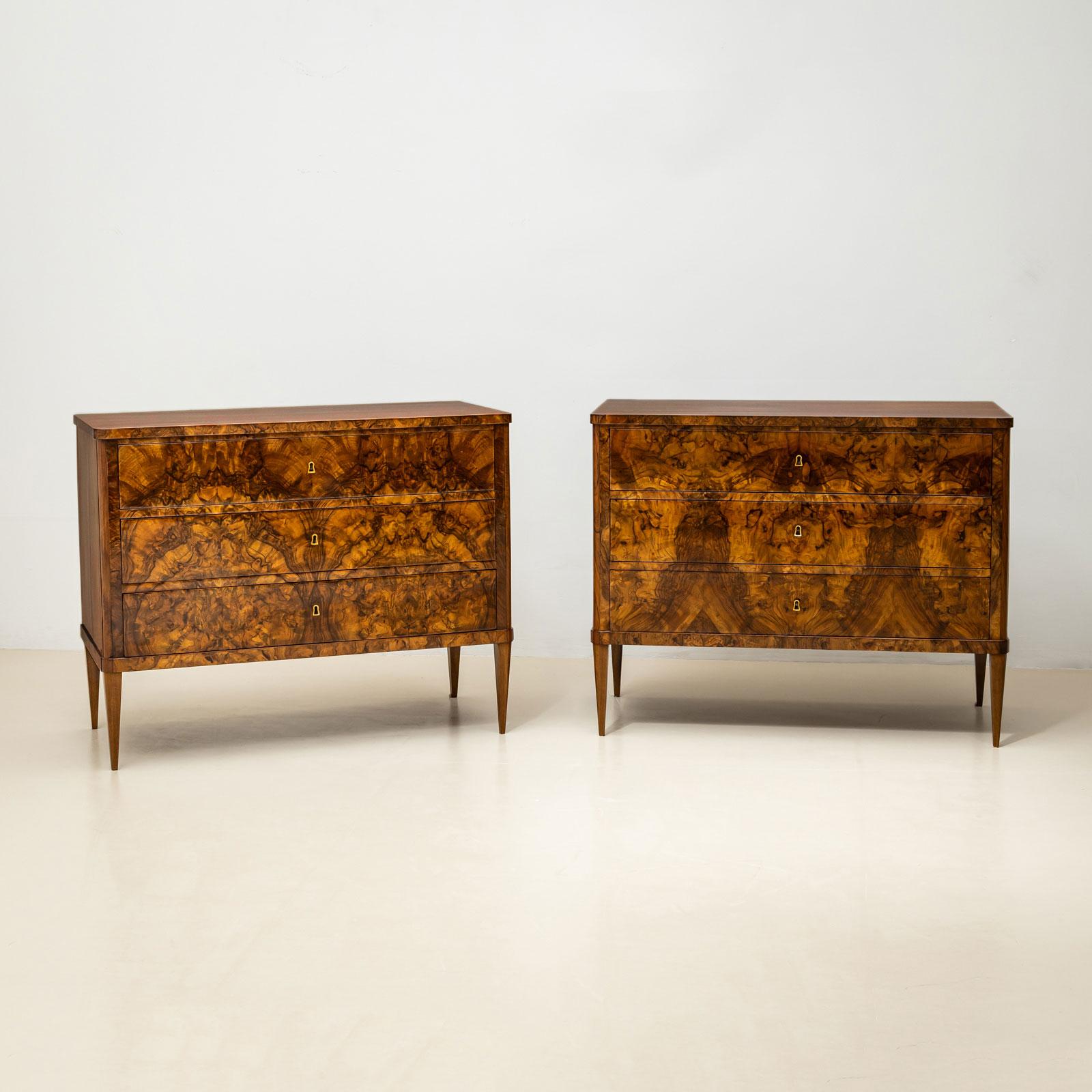 

Un par de cómodas Biedermeier de Italia, fabricadas hacia 1830. Las cómodas presentan una llamativa chapa de nogal espejada, que realza su elegante aspecto. Las bocallaves forradas de latón añaden un detalle refinado.

Las cómodas se apoyan en