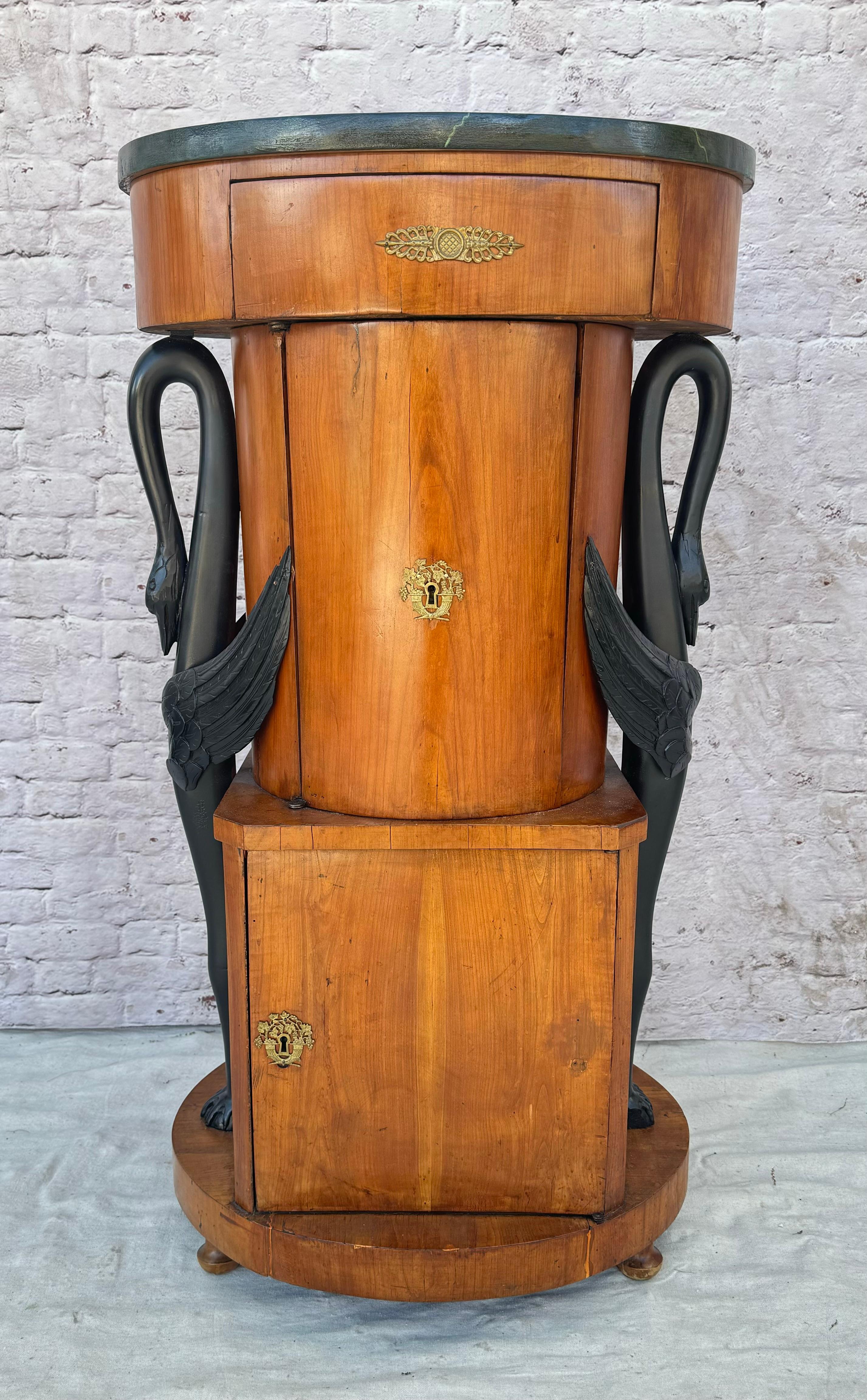 Rare 19th Century Biedermeier Walnut Cabinet with Faux Marble Top. Cabinet features beautiful rich walnut with elongated ebonized birds on either side and round black faux marble top.  Round top piece has one small drawer with brass handle, Center