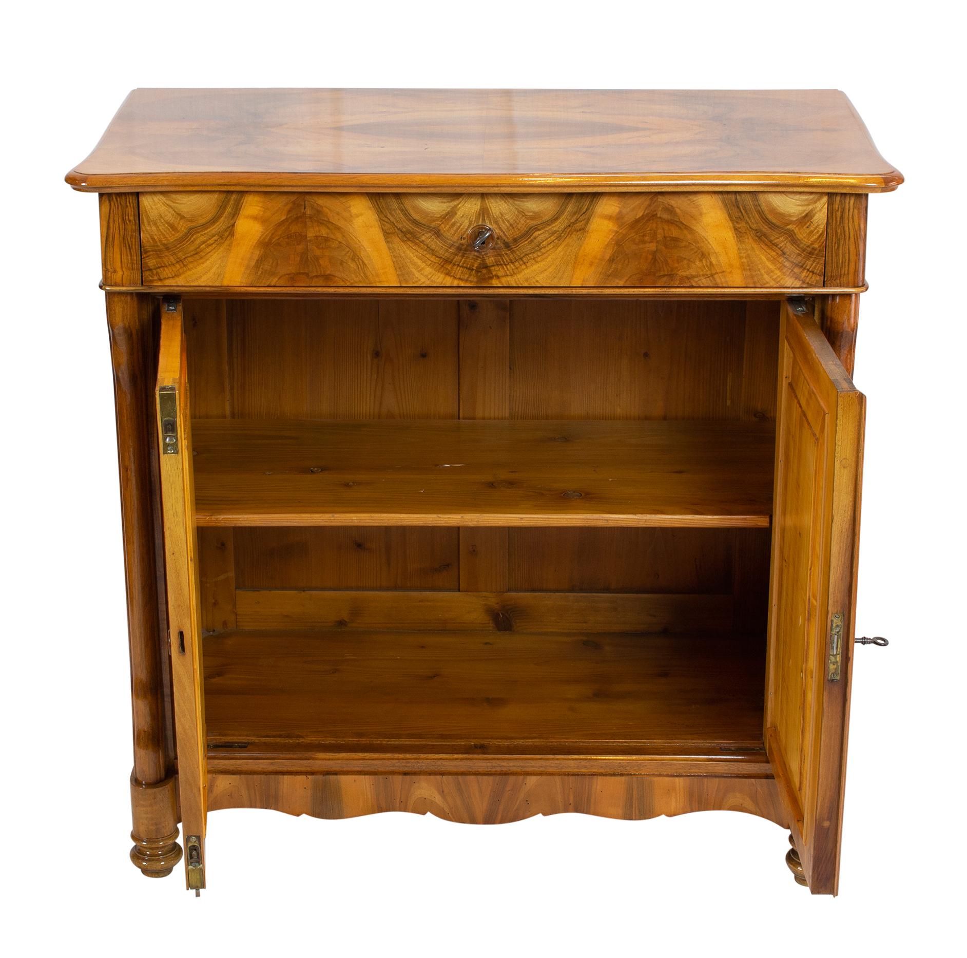 Schöner Biedermeier Halbschrank aus der Zeit des späten Biedermeier / Louis Philippe, um 1845. Die Möbel sind mit schönem Nussbaumfurnier auf einem Fichtenkorpus überzogen.
Oben befindet sich eine Schublade, darunter sind zwei Türen. Äußerst
