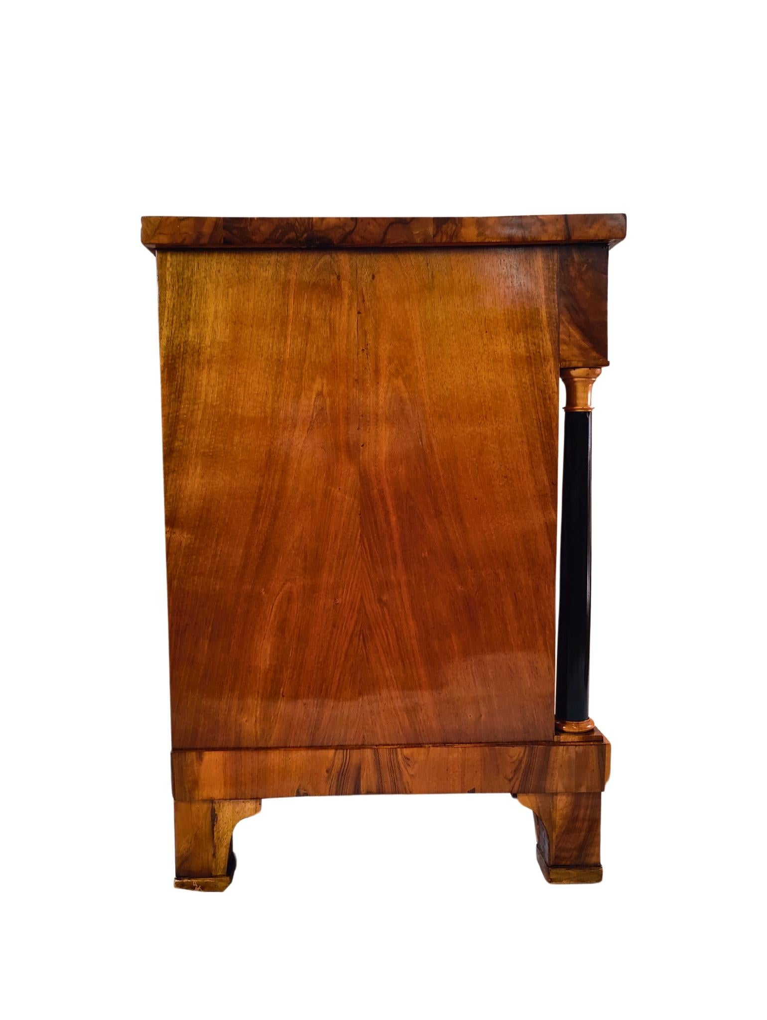 Scopri l'eleganza senza tempo di questo imponente semi-armadio Biedermeier, realizzato con una splendida impiallacciatura di noce. Questo squisito pezzo presenta un ampio cassetto nella parte superiore e due ante nella parte inferiore, il tutto