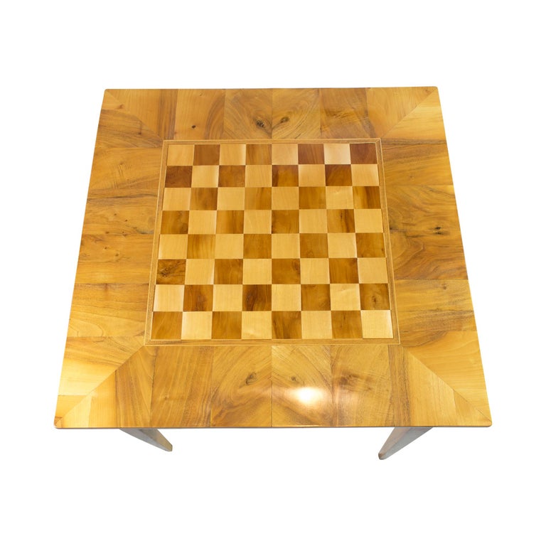 A classic Biedermeier table from the period. The table was made mainly of walnut wood. The surface has a large chessboard made by a marquetry work with maple and walnut wood. The table stands on four pointed legs, very classic for Biedermeier. The