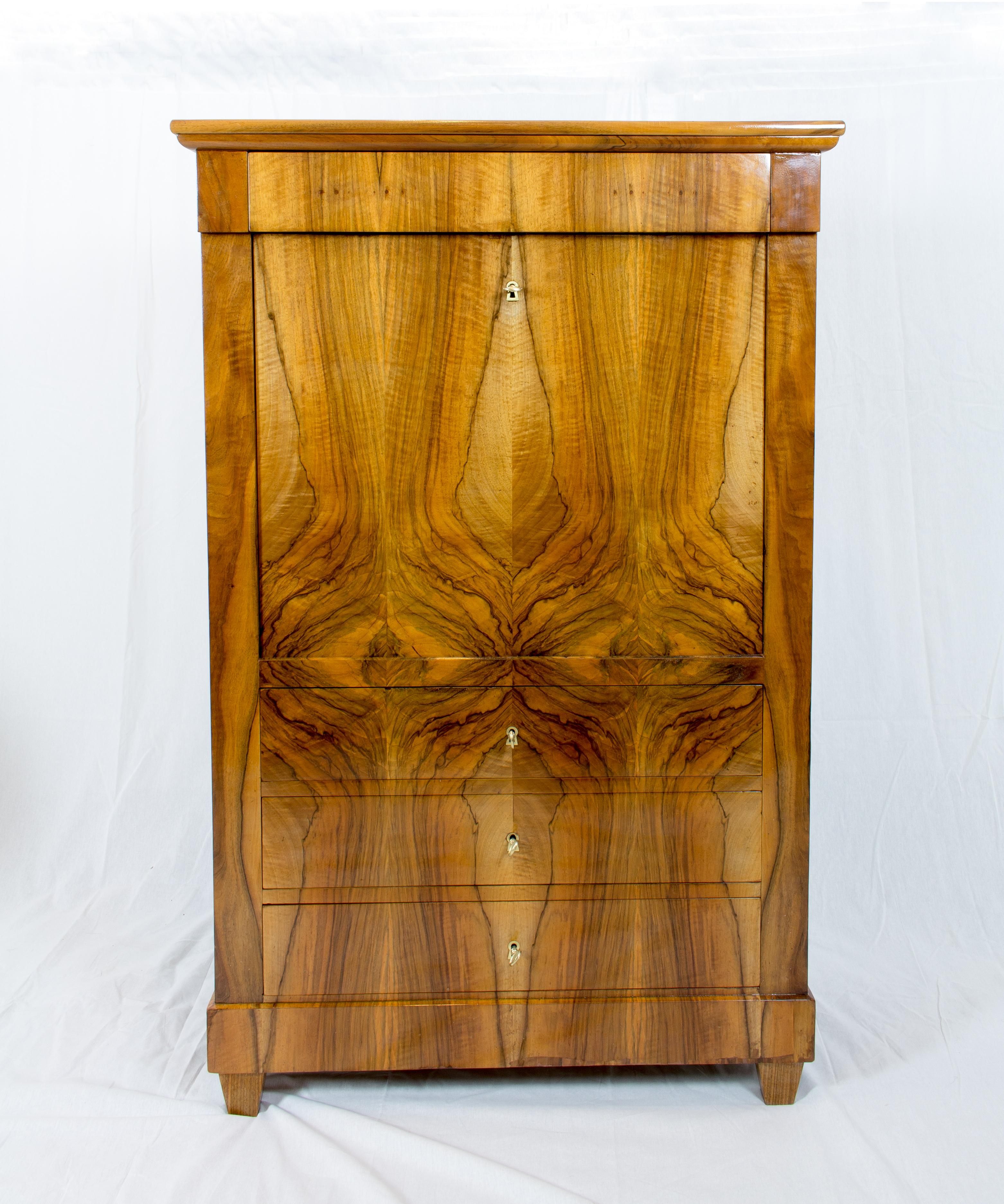 A beautiful small Secretaire made of walnut veneer from the time of Biedermeier. The Secretaire is outside covered with a beautiful walnut veneer picture and the interior is made of solid cherry wood. 
Under the middle lower drawers in the centre,