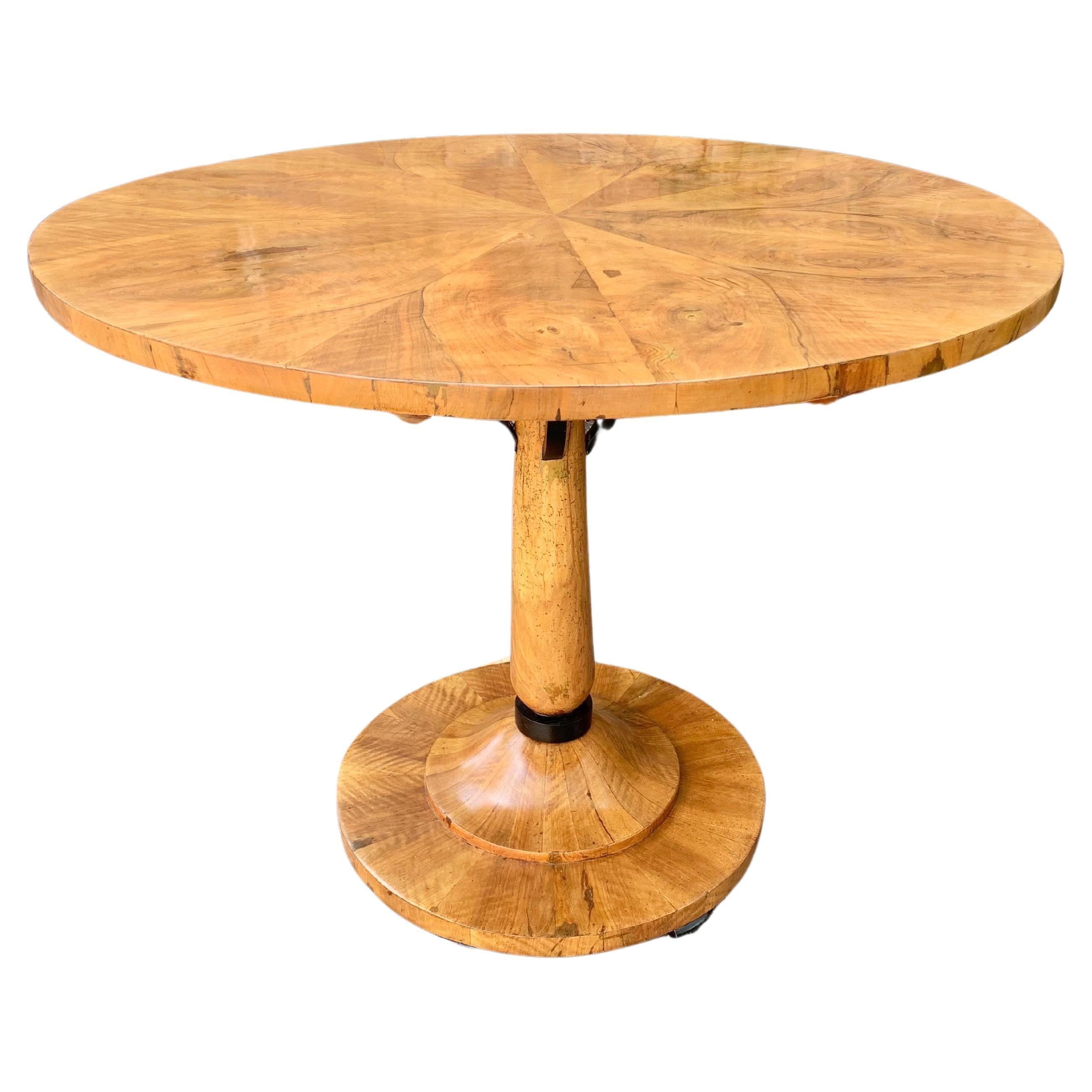 This stunning Biedermeir Pedestal Table, was crafted by furniture artisans in the 19th Century. The table features a beautiful book matched walnut veneered top, pedestal base and rounded bottom resting on six ebonized feet. The piece is accented by