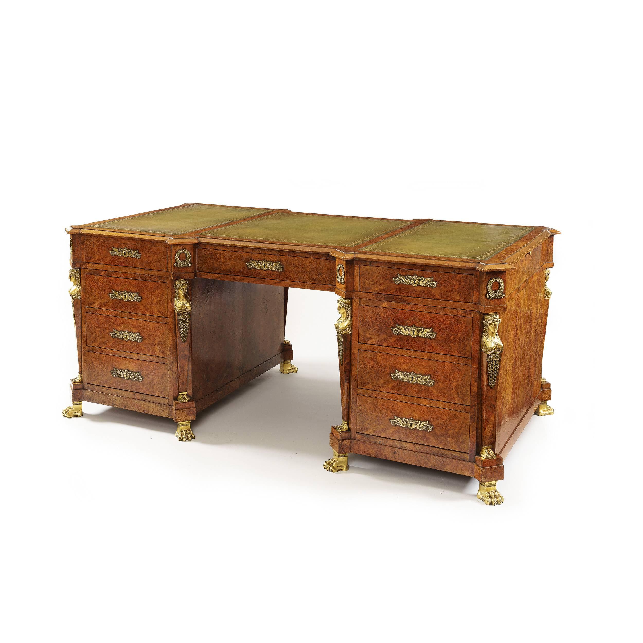A pedestal desk in the French Empire manner

of freestanding breakfront form with everted angles, constructed in birchwood, and burr birchwood, having bronze accents drawn from the oeuvres of Percier and fontaine; rising from bronze lions' paw
