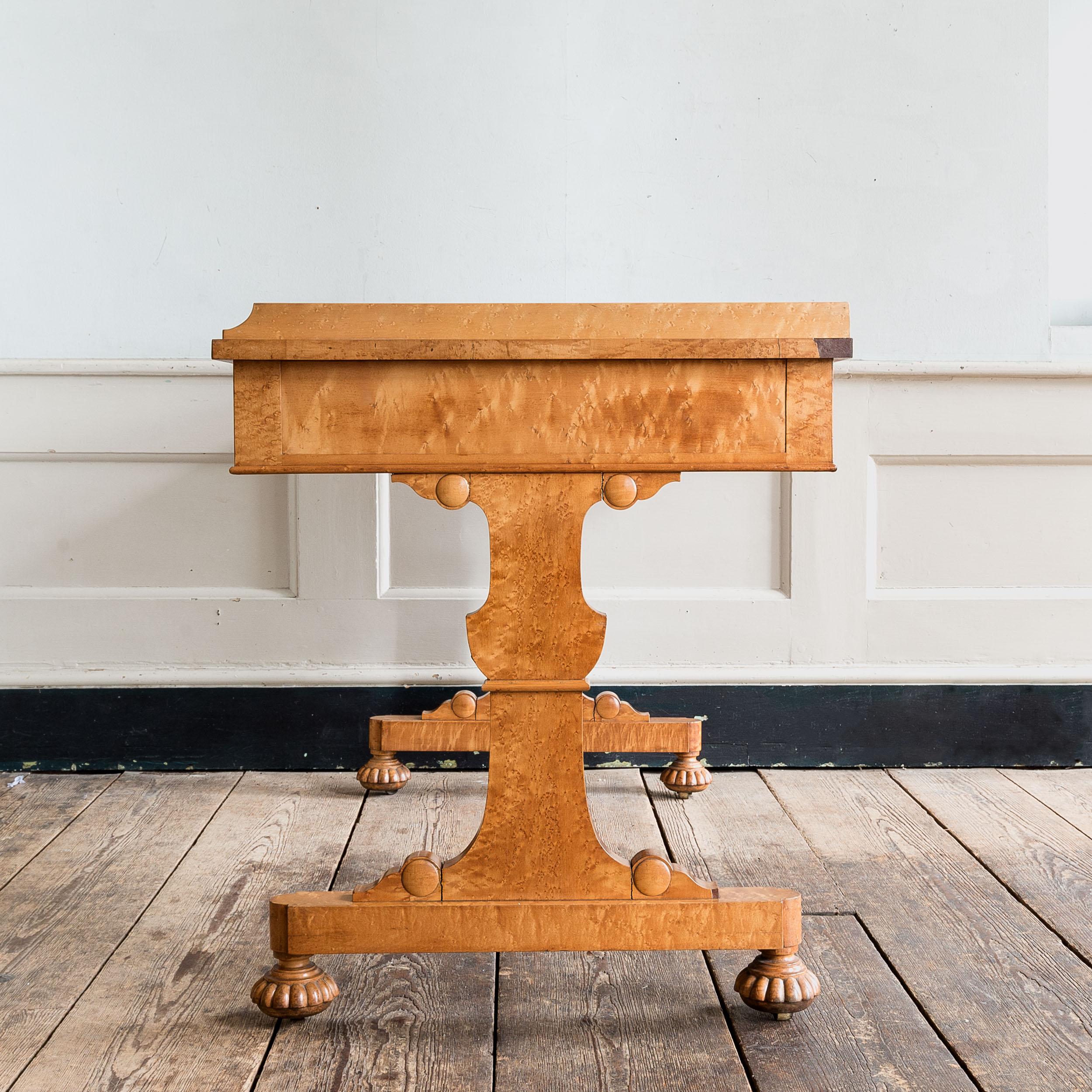 A fine nineteenth century bird’s eye maple library table by Gillows of Lancaster, c.1830, with three-quarter gallery to the top, the frieze with three drawers, the twin shaped supports with gadrooned feet and castors.