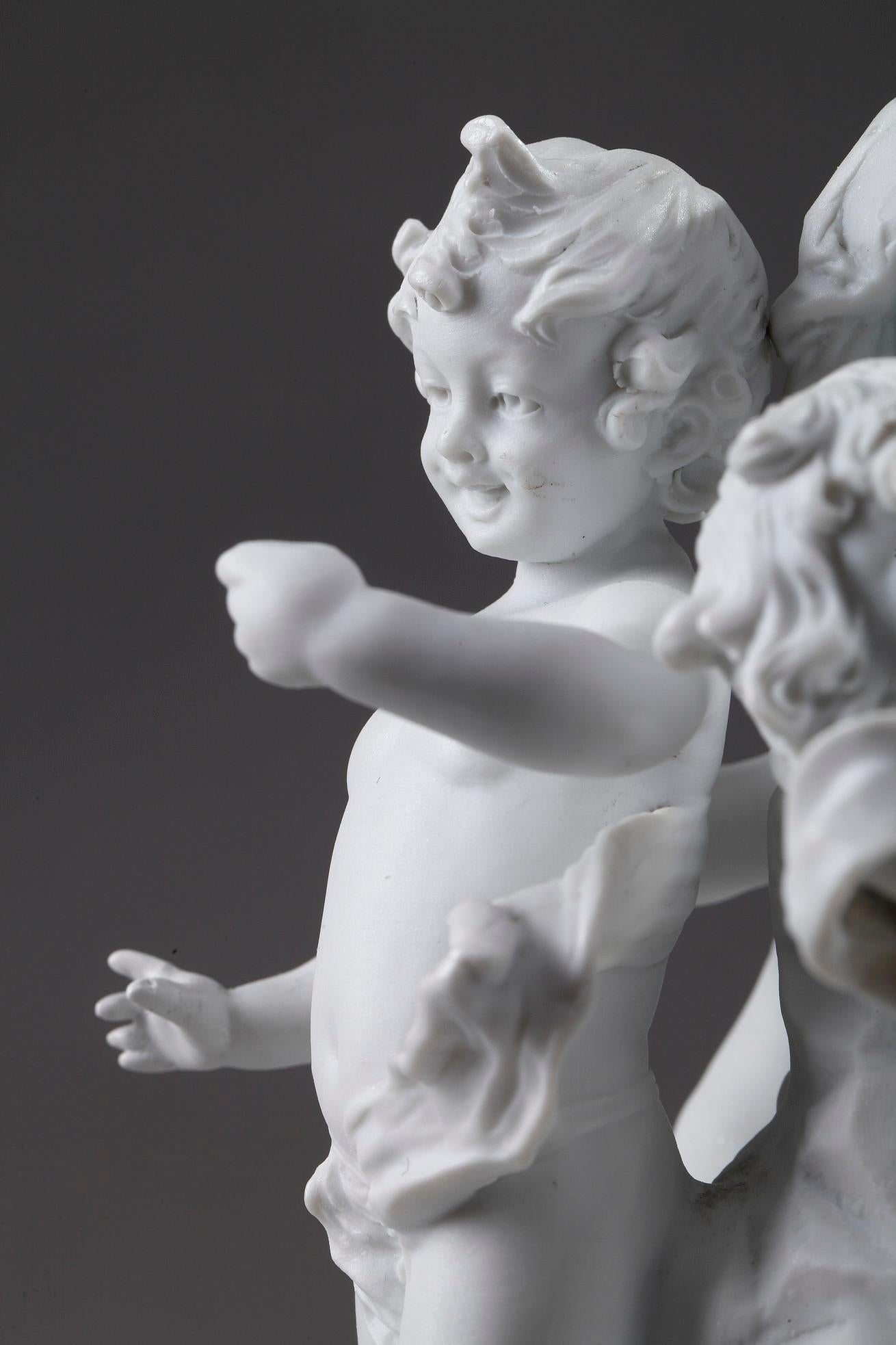 Small bisque porcelain figurines featuring five putti holding a cup, an insect and a shell. Four of them are dancing around a central rock, topped by a fifth cupid, crowned with vine leaves and holding a cup. The crown of vine branches and the cup
