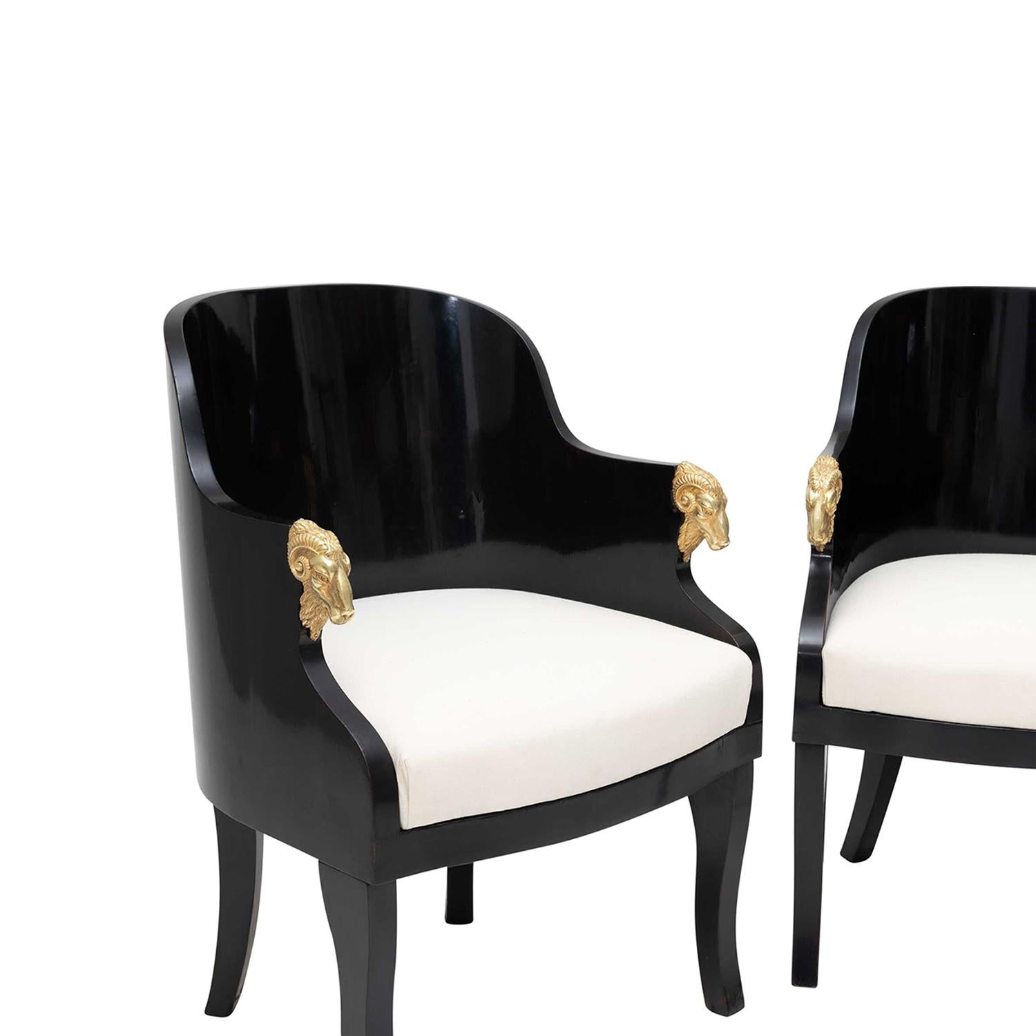 A 19th Century, antique Baltic pair of black armchairs made of hand crafted lacquered Birchwood, in good condition. The small detailed side, club chairs have a rounded back with slim armrests, particularized by gilded goat heads, standing on four