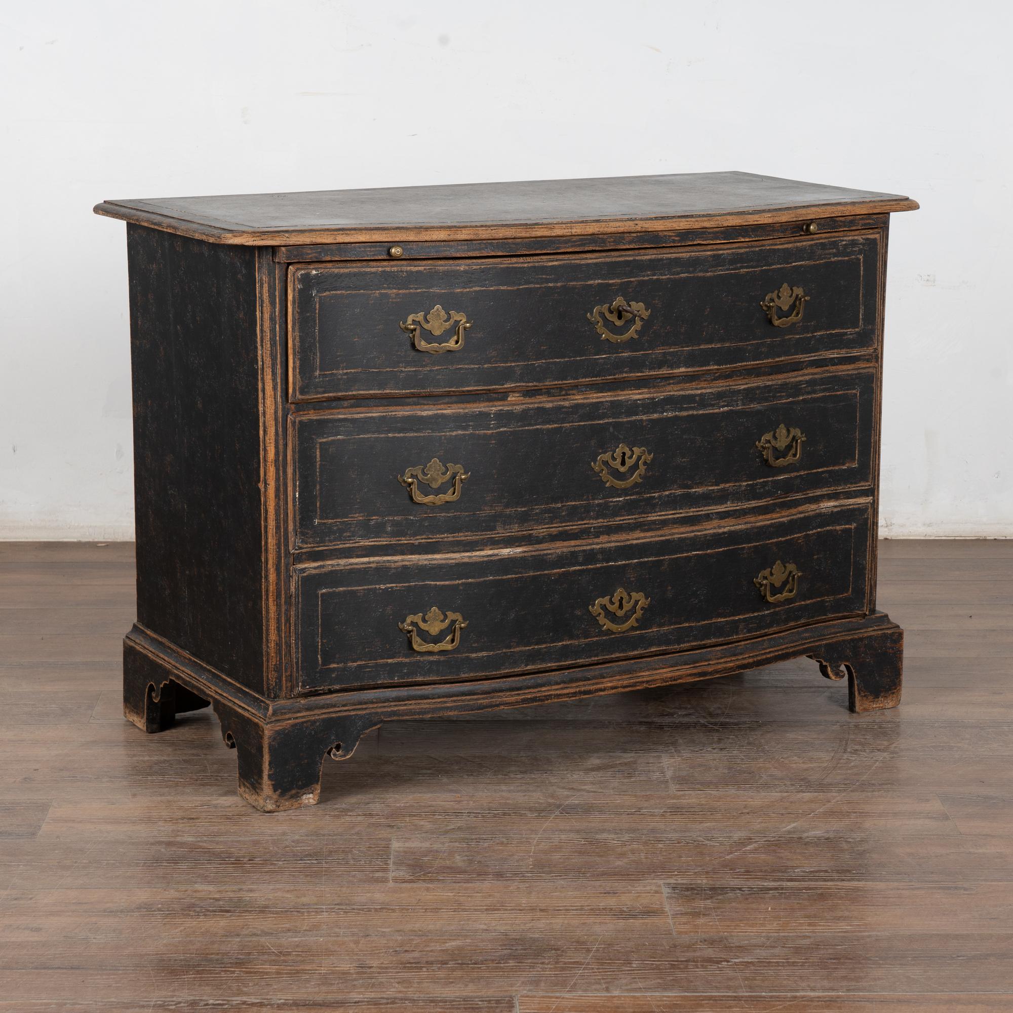Antique baroque chest of three drawers from Sweden, circa 1800's. The black painted finish has been lightly scraped exposing the natural wood beneath and highlighting the details of the casework.
The slight contours of the top are repeated in each