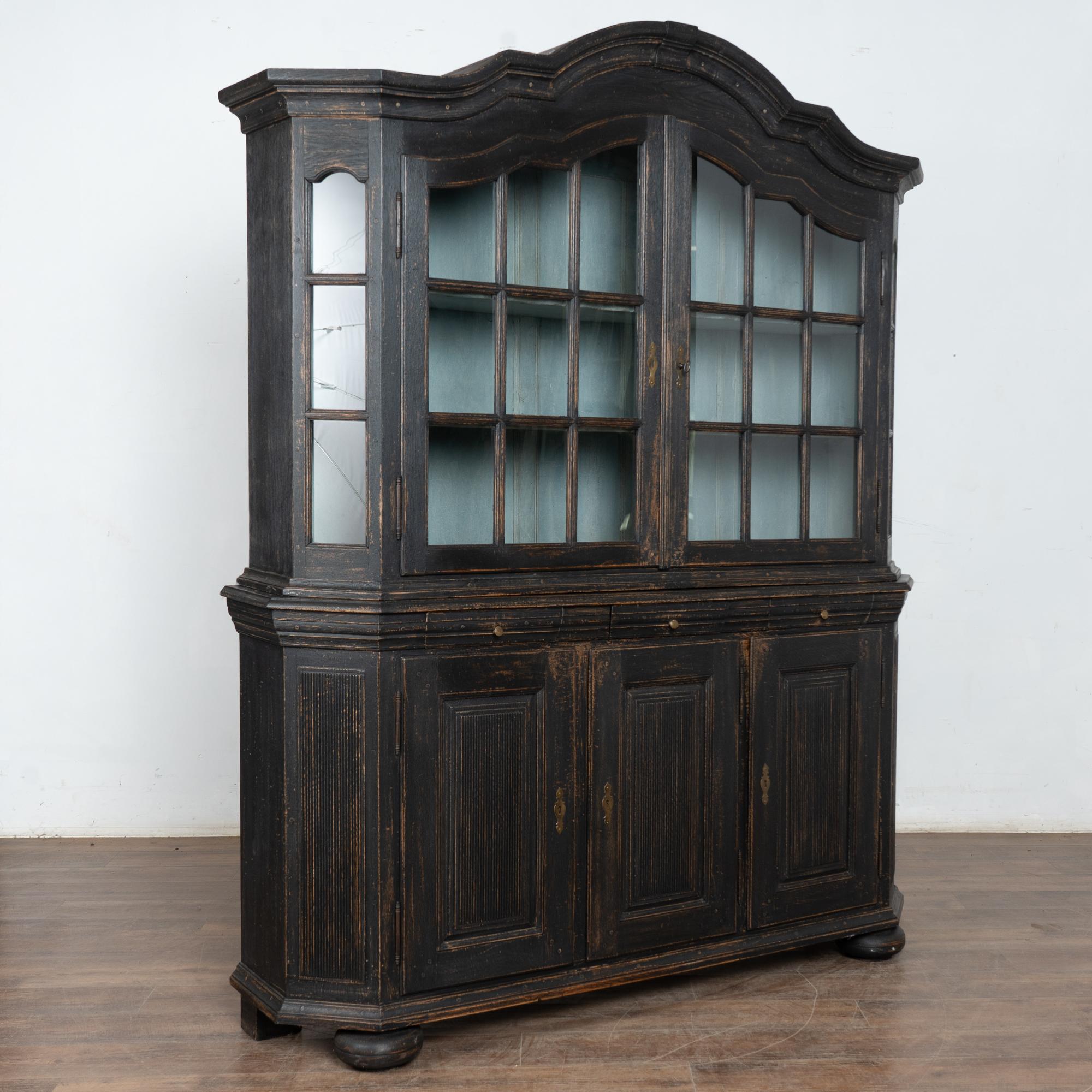Cette armoire danoise peut être utilisée comme vitrine ou bibliothèque. Les portes vitrées supérieures permettent une belle mise en valeur des collections qu'elles contiennent.
La nouvelle finition peinte en noir, appliquée par des professionnels,