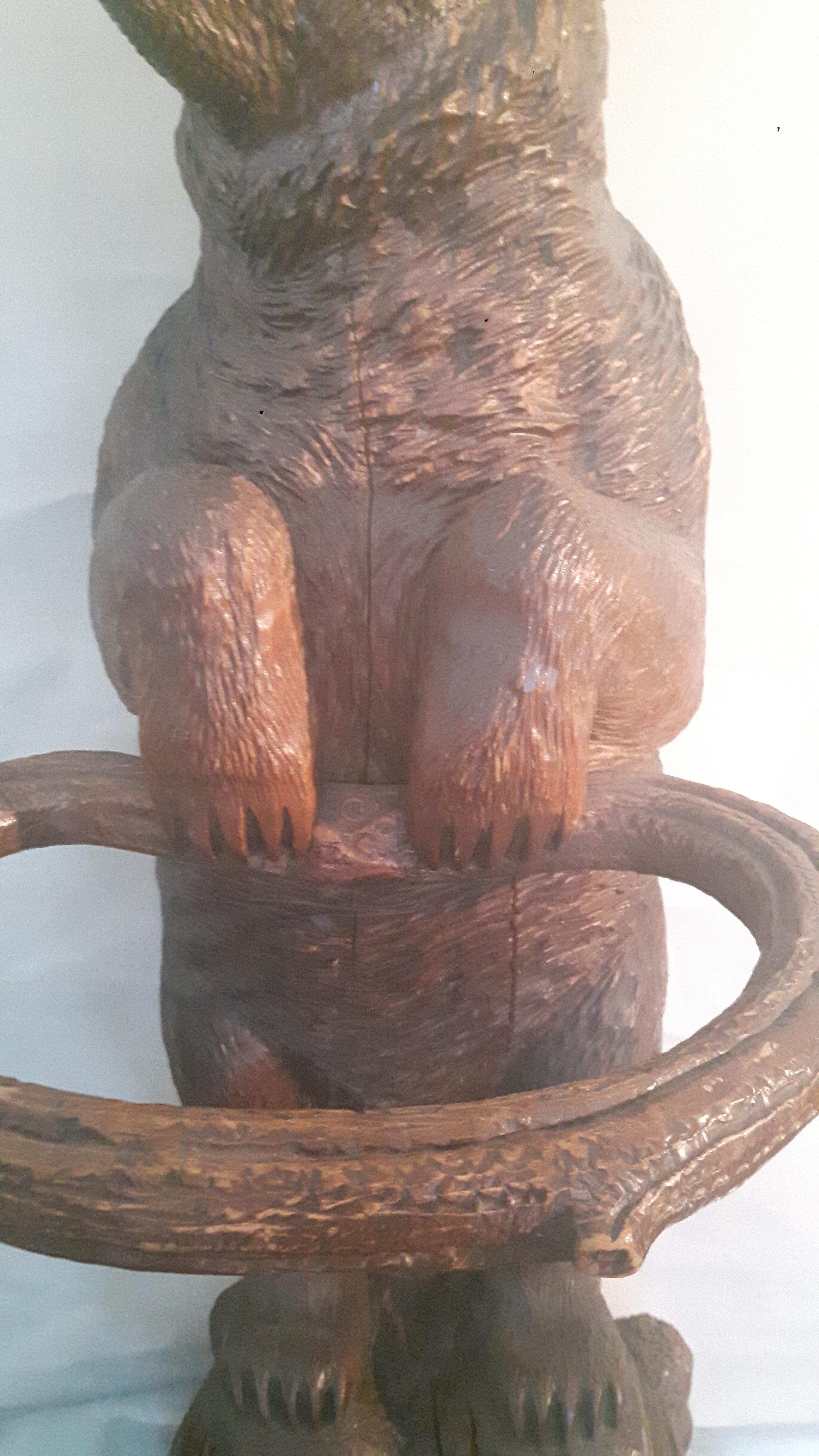 Un grand ours de la Forêt Noire en forme de bâton se tient sur un socle rocheux avec une expression rugissante, la langue rouge tachée.