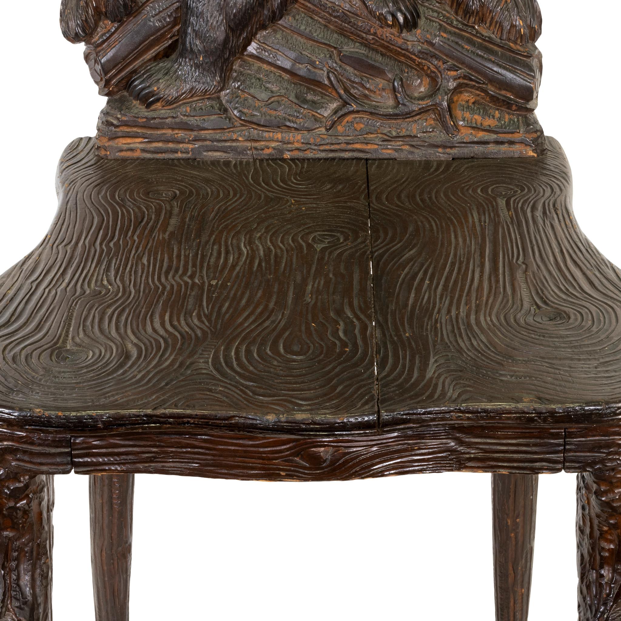 Black Forest Swiss carved chair having bear on fallen log. Carved bear on lifting seat which once had a music box. Part of the Brienz collection plate 26. 

Origin: Swiss
Period: Last quarter of the 19th century
Dimensions: 38