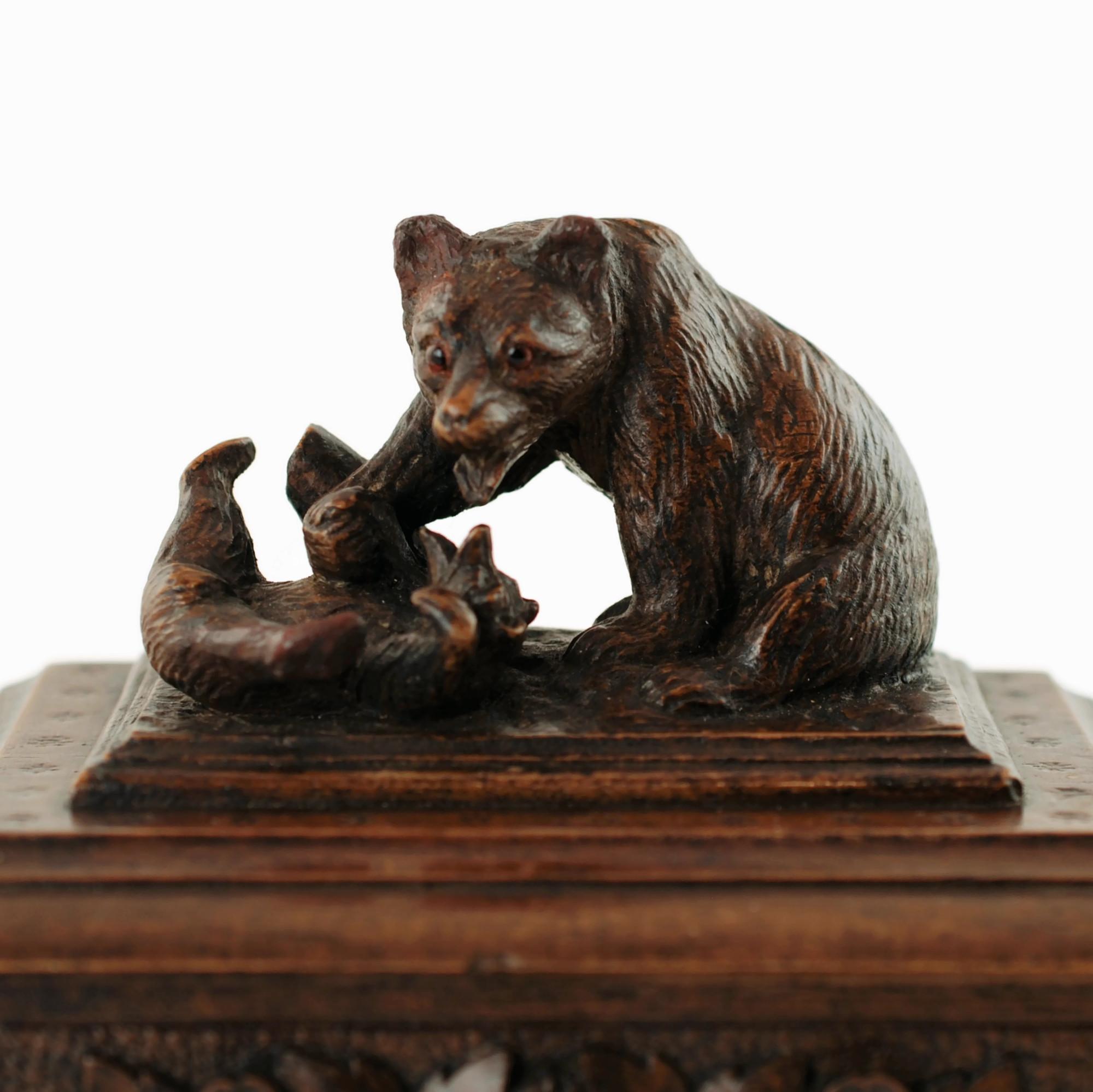 Cette boîte antique inhabituelle de la Forêt-Noire représente une paire d'ours de toutes les dimensions s'ébattant à la base d'une souche d'arbre. La mère et l'ourson ont été finis avec un haut niveau de détail, y compris des yeux en verre dans la