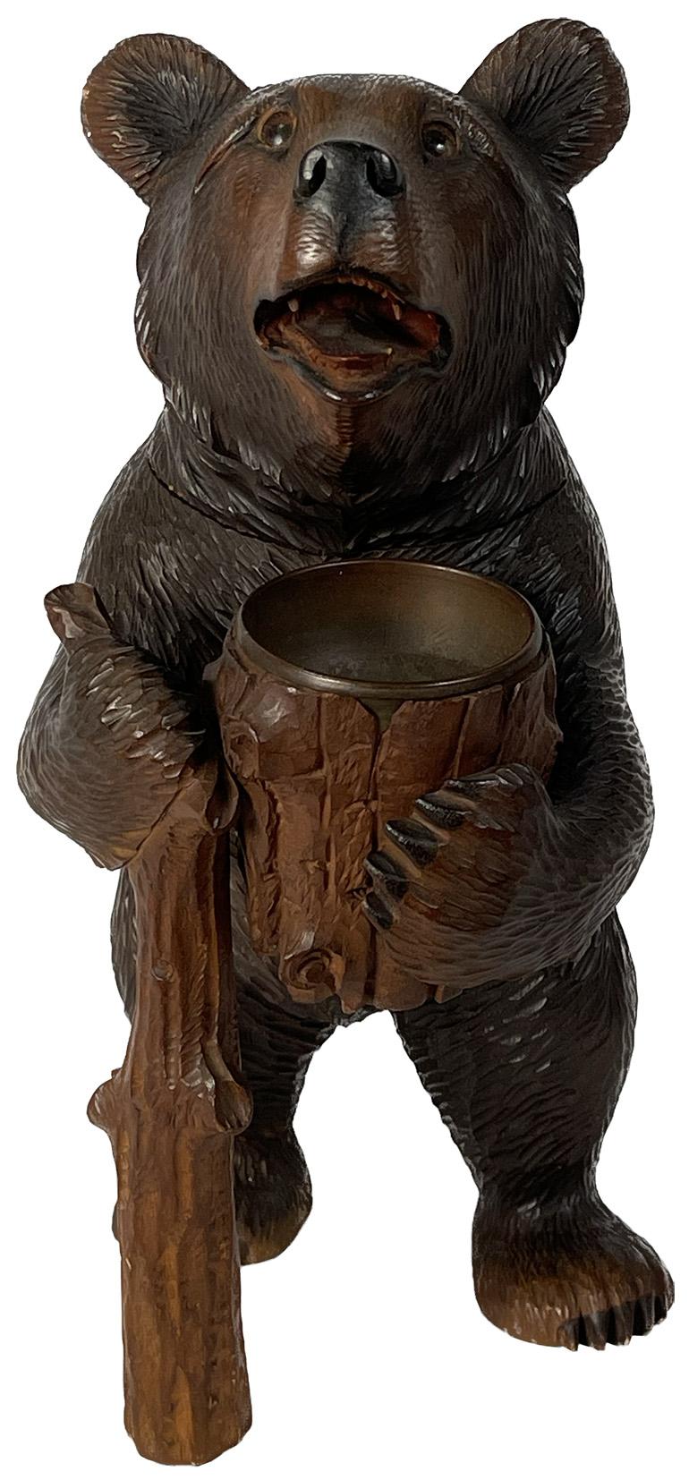Late 19th century carved black Forest standing bear with glass eyes, holding a metal lined bowl with an opening hinged head.

Measures: 7