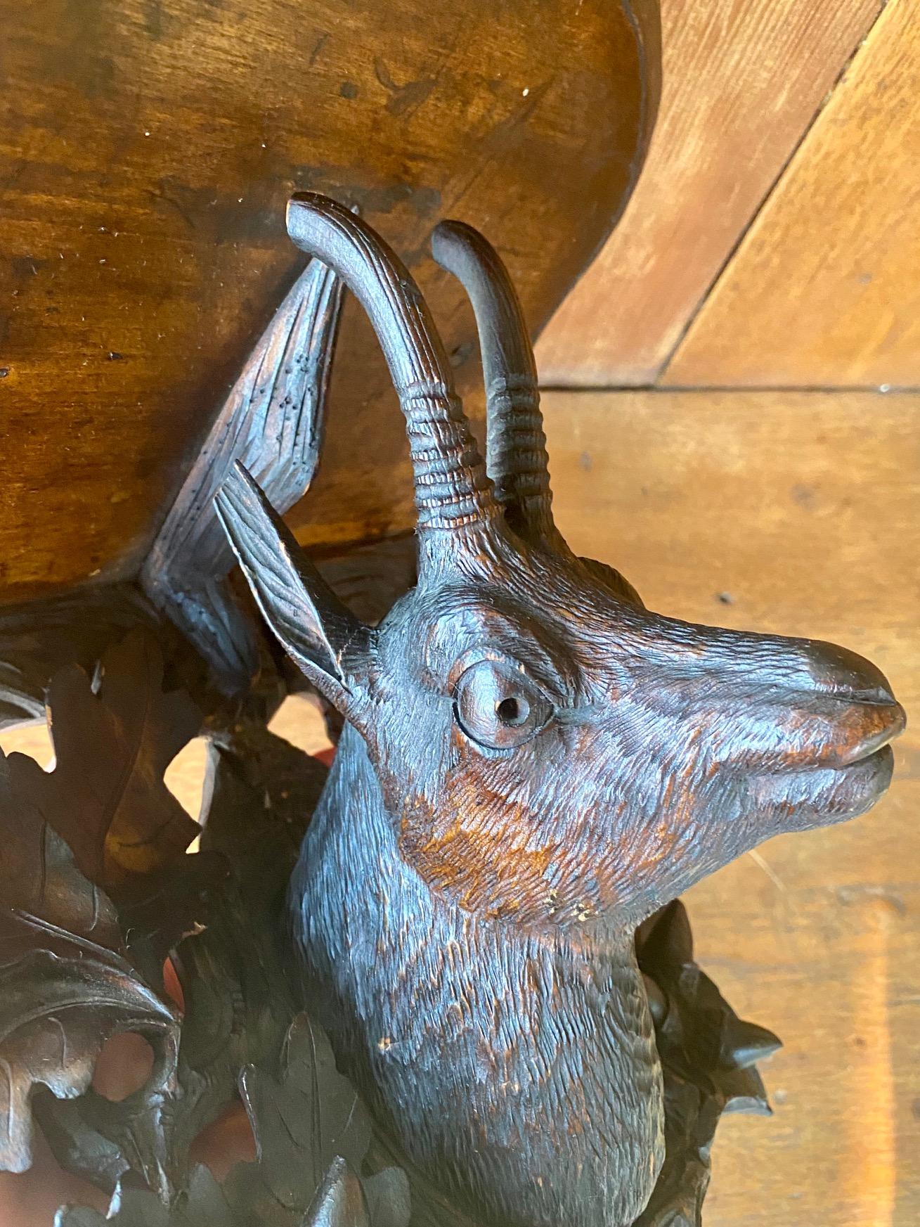 19th century Black Forest carved bracket shelf, circa 1870, a hand carved walnut bracket shelf with shaped top above a very well carved chamois head with glass eyes, set on carved oak leaf surround, in original dark stain. These folk art carvings