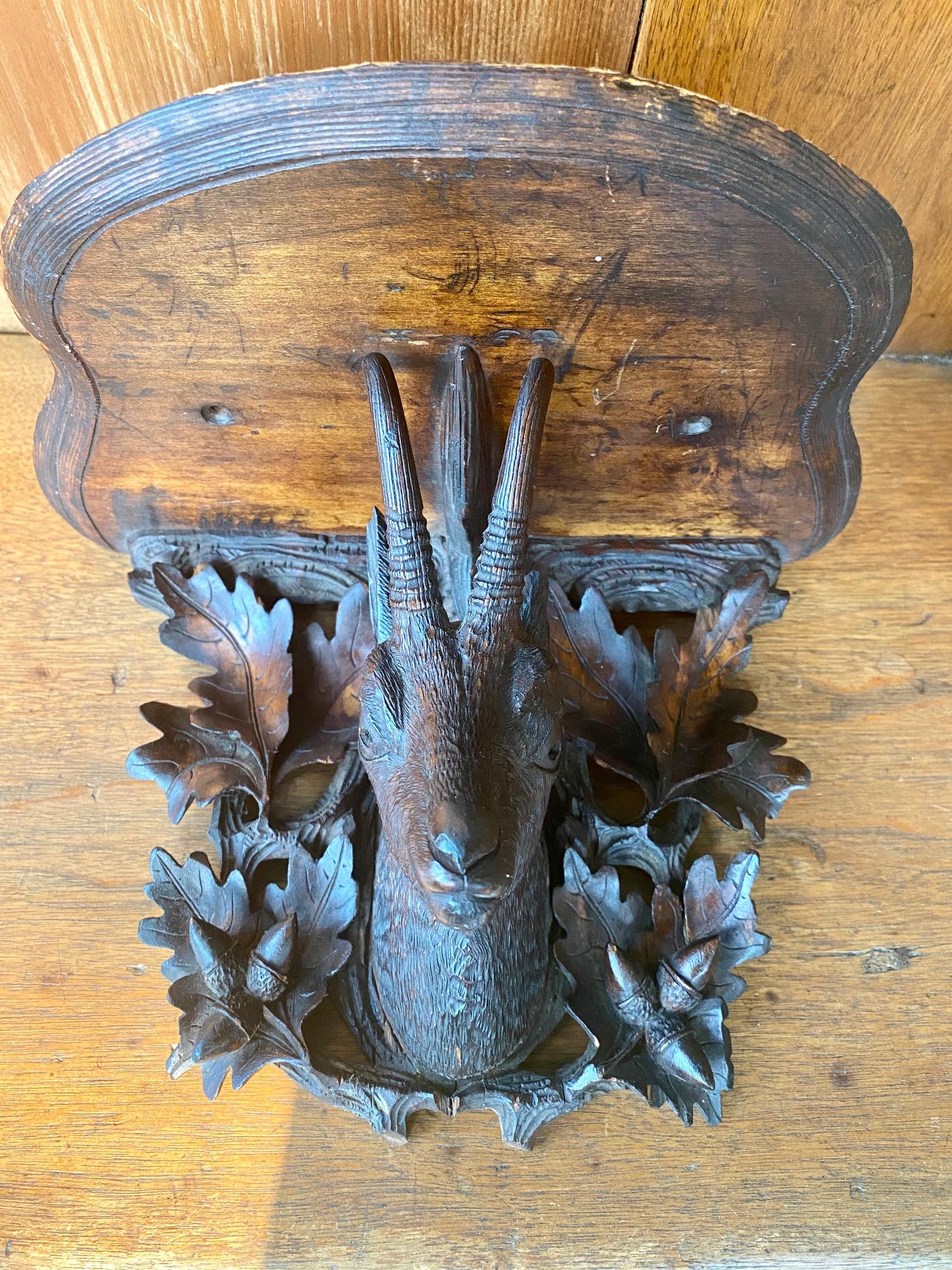 19th century black forest carved bracket shelf, circa 1870, a hand carved pine bracket shelf with shaped top above a very well carved chamois head with oak leaf and acorn surround, in original dark stain. These Folk Art carvings are called 