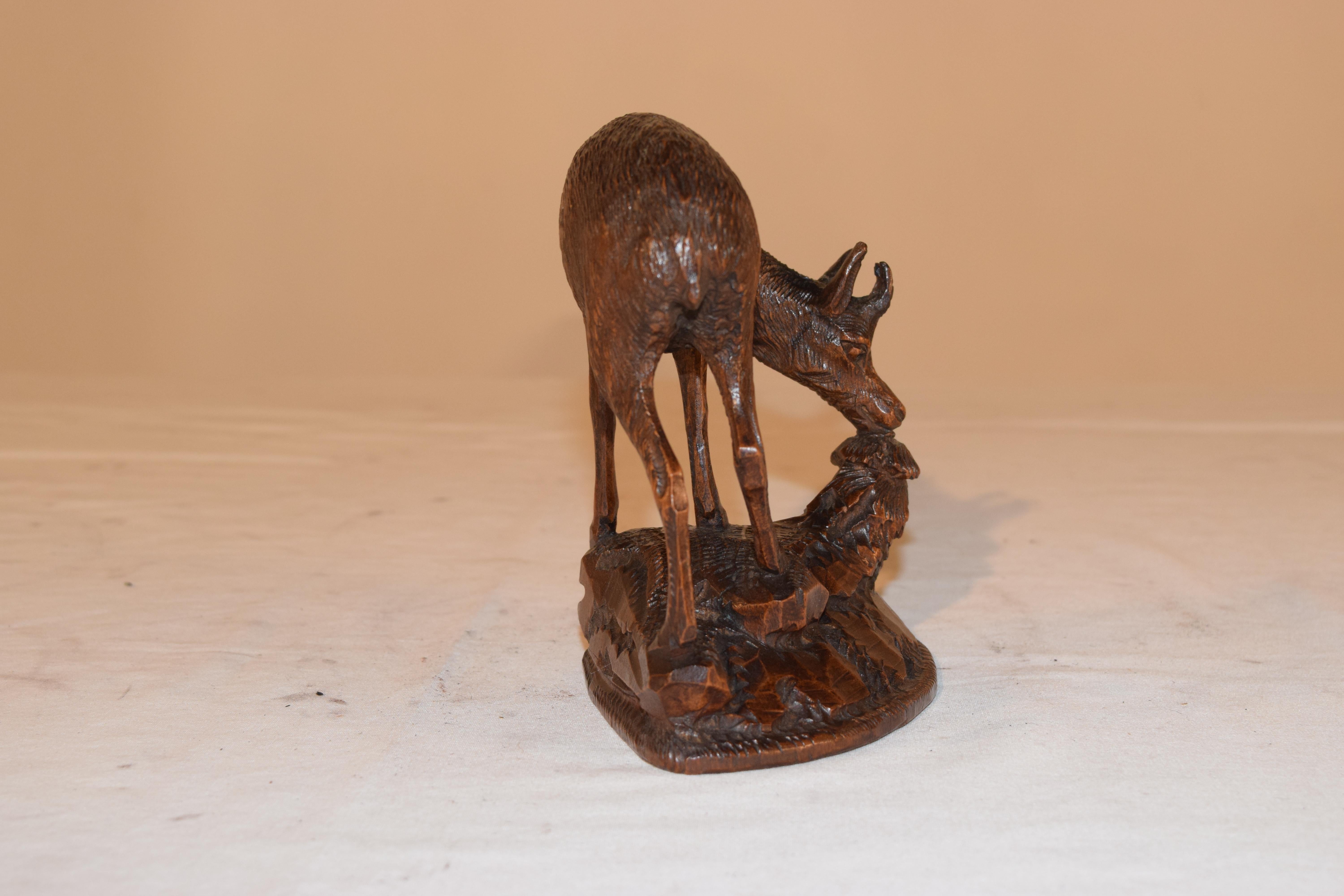 19th century Black Forest hand carved figure of a Chamois deer, bending down to eat foliage. The carving is lovely and in very good condition for its age.