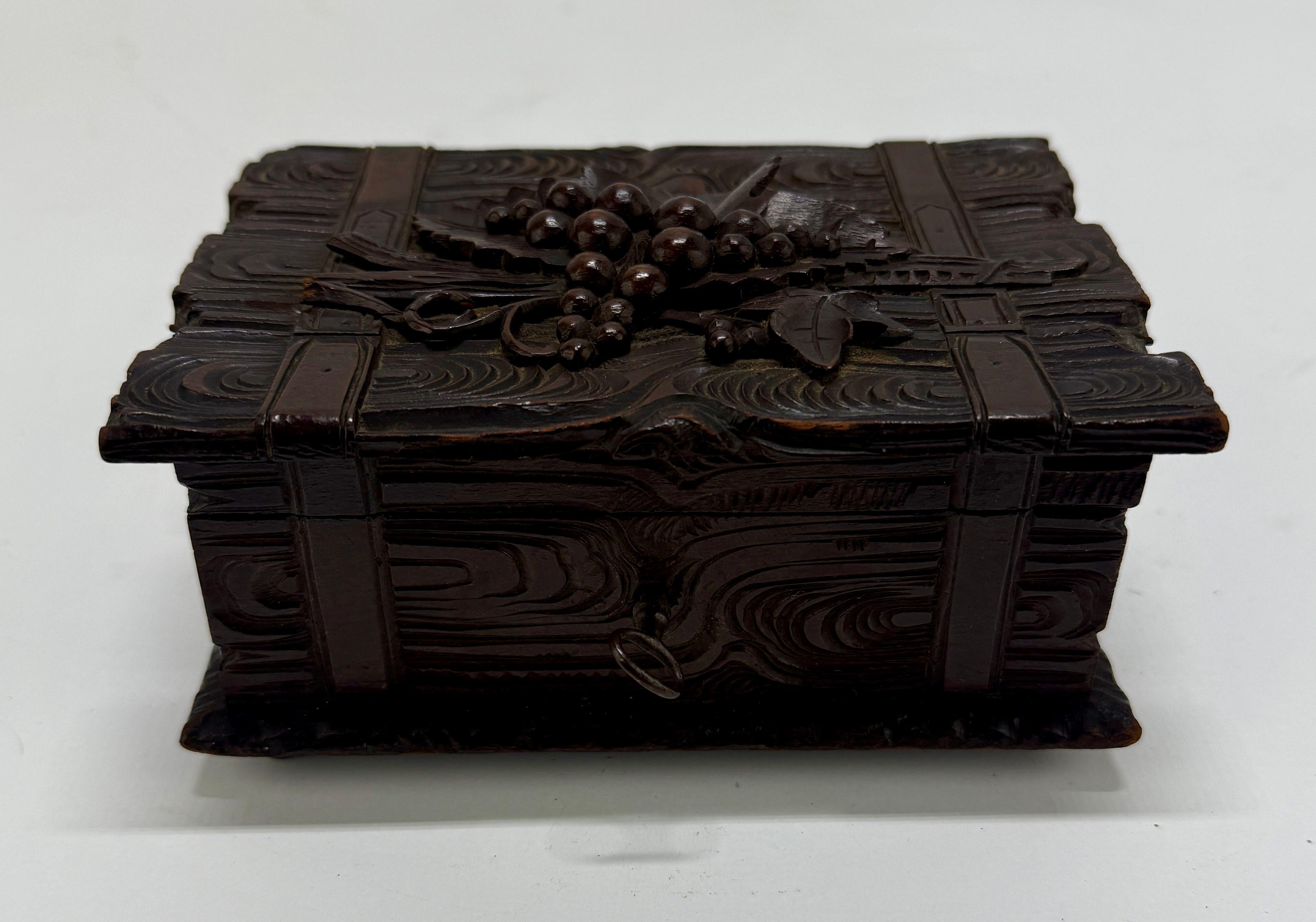 An unusual and visually striking carved wooden presentation box, Black Forest region, circa 1880. The box is carved in the form of a stacked book bundle tied with strapwork, its surfaces rendered in a stylized faux bois pattern emulating woodgrain.