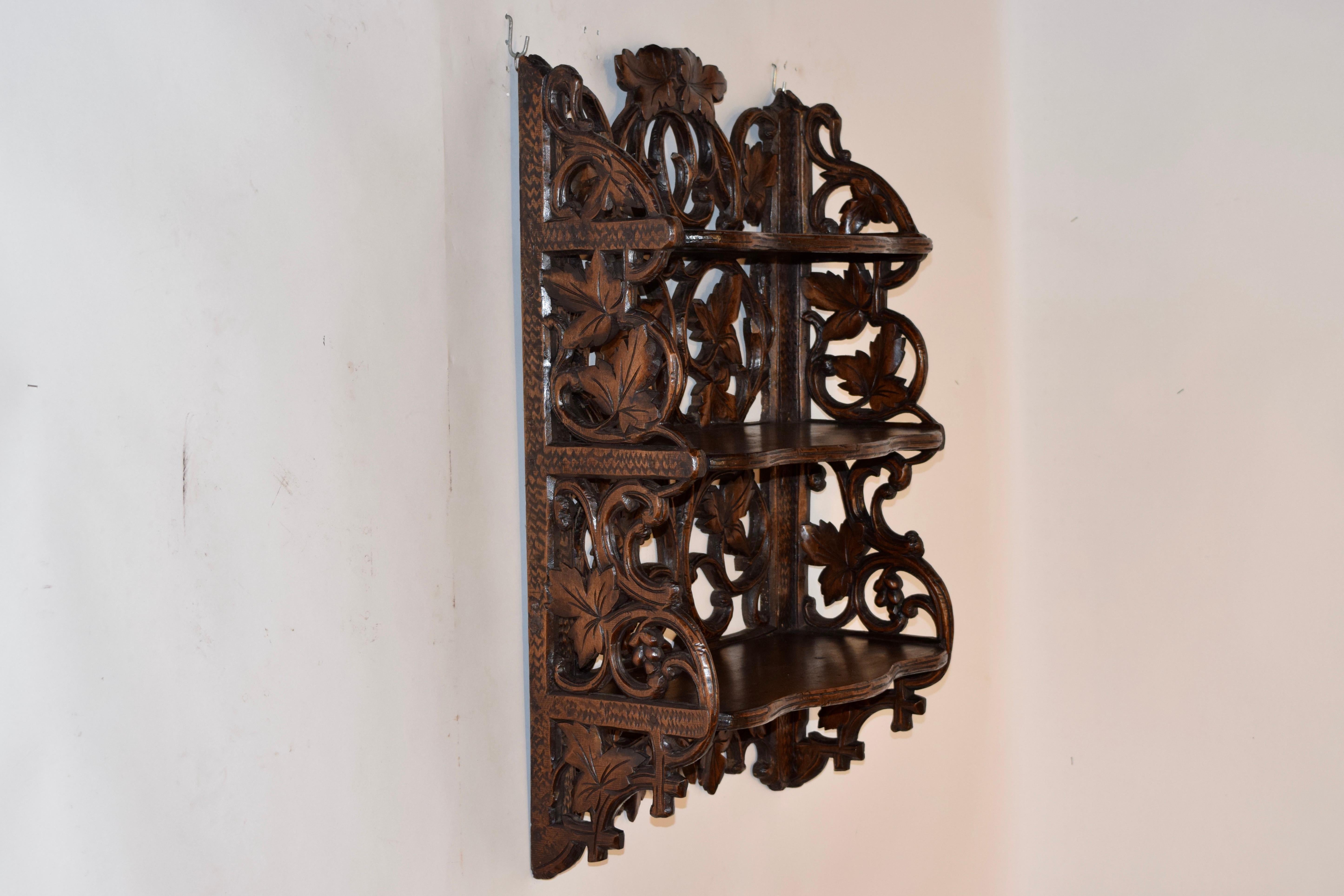 19th century Black Forest hand carved wall shelf from Switzerland with three shelves, all with hand carved faux bois decoration on the fronts of the shelves. The back of the shelf is highly carved with branches and leaves, and the sides of the shelf
