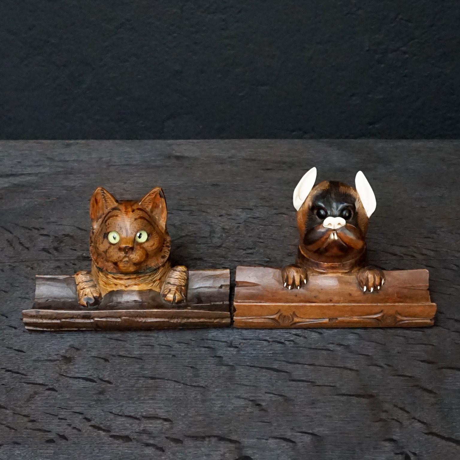 Sehr hübsches Set aus zwei geschnitzten Hunde- und Katzenköpfen aus Nussbaumholz aus dem 19. Jahrhundert mit Glasaugen und Tintenfass mit Federhalter aus Holz. 

Aufwändig geschnitzte Details an Haaren, Zähnen, Augen und Pfoten. 
Die Katze hat grüne
