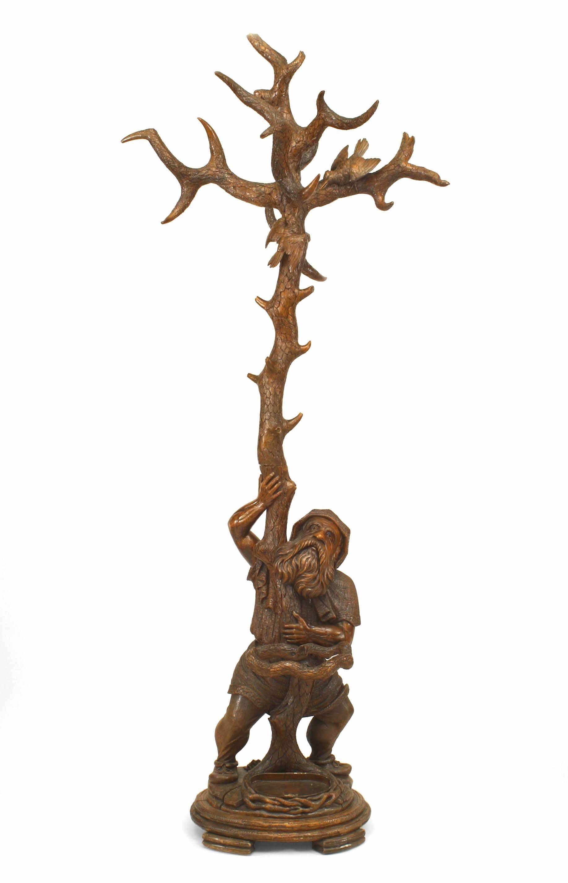 Rustic Black Forest-style (19th Century) carved walnut hatrack/umbrella stand with gnome figure holding tree form with birds in upper branches.
