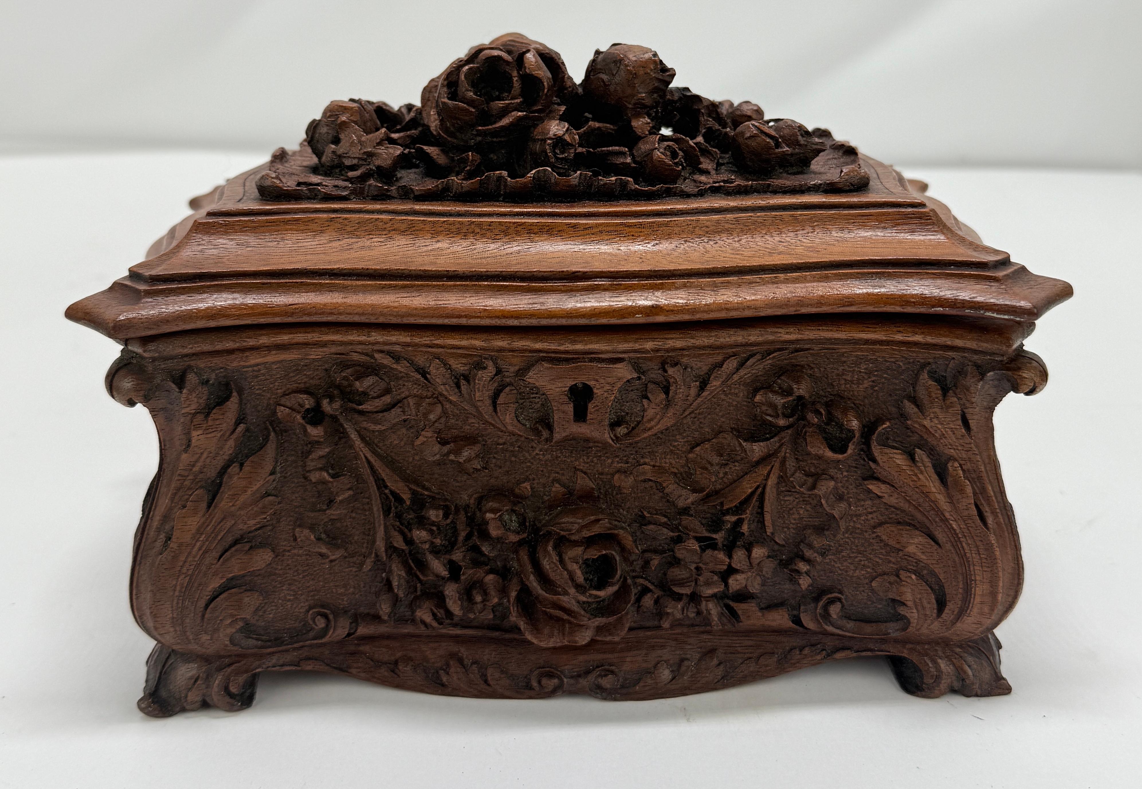 A finely carved 19th-century Black Forest walnut jewelry casket, attributed to the Brienz region of Switzerland, distinguished by its lavishly naturalistic ornamentation and sculptural detailing. The exterior is deeply carved with flowing rocaille