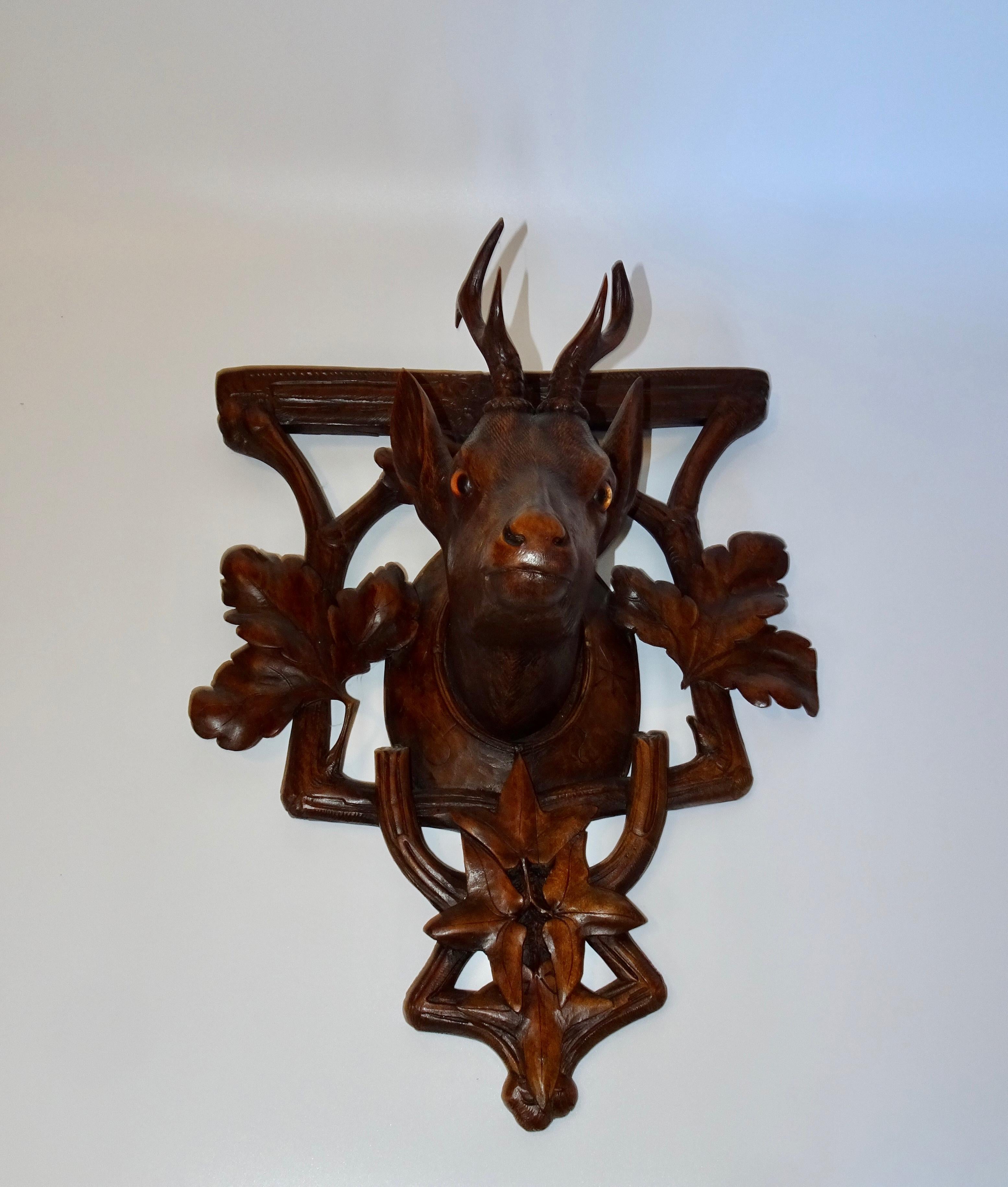 This is a beautiful 19th century black forest carving of a deer head on a carved plaque. The plaque has carvings of leaves and branches.