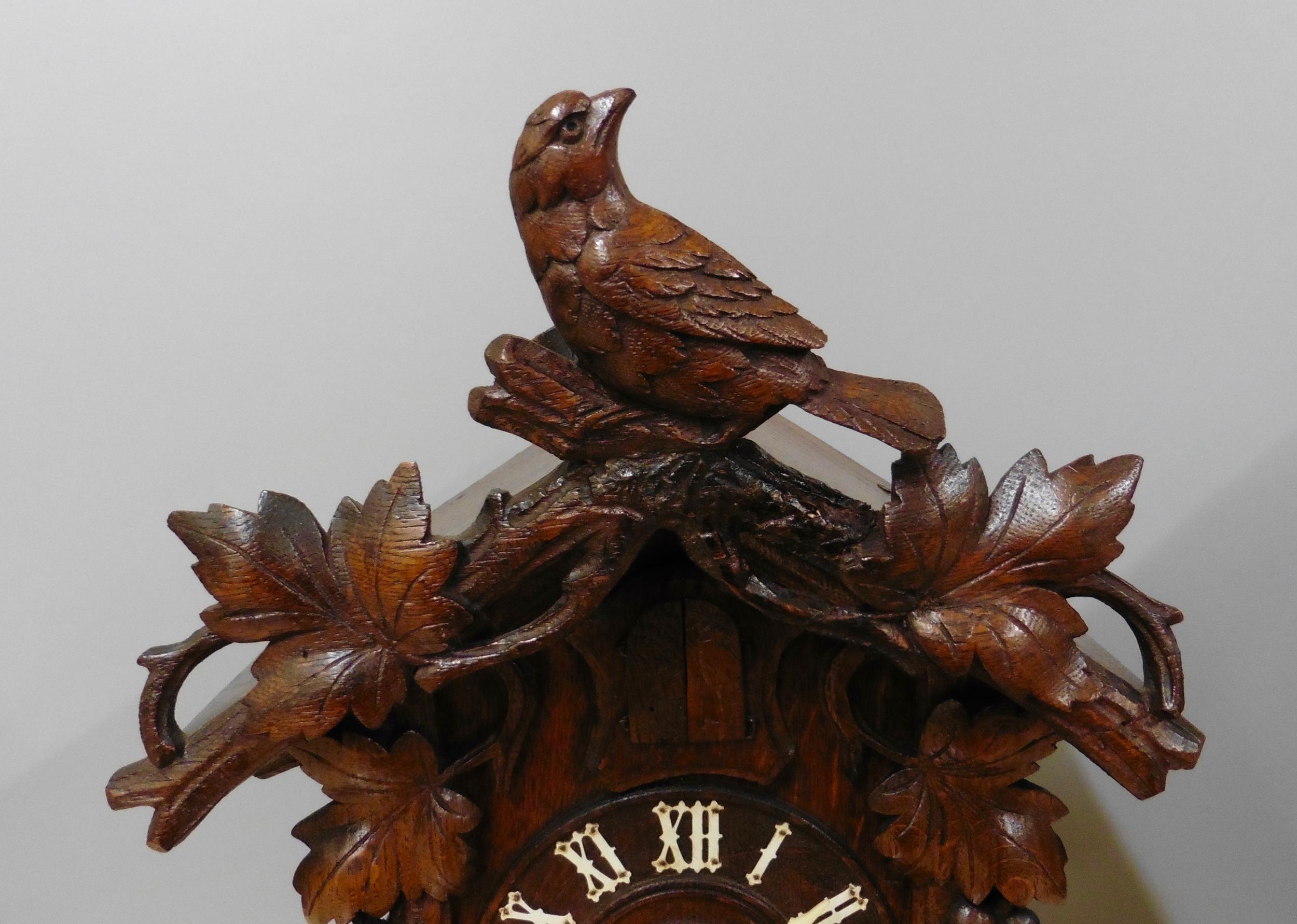 Nineteenth century Black Forest mantel Cuckoo clock in a chalet style case surmounted by a finely carved bird with ivy cresting over a foliate clad exterior and surrounding carved fence.

Five inch dial with Roman numerals and carved bone