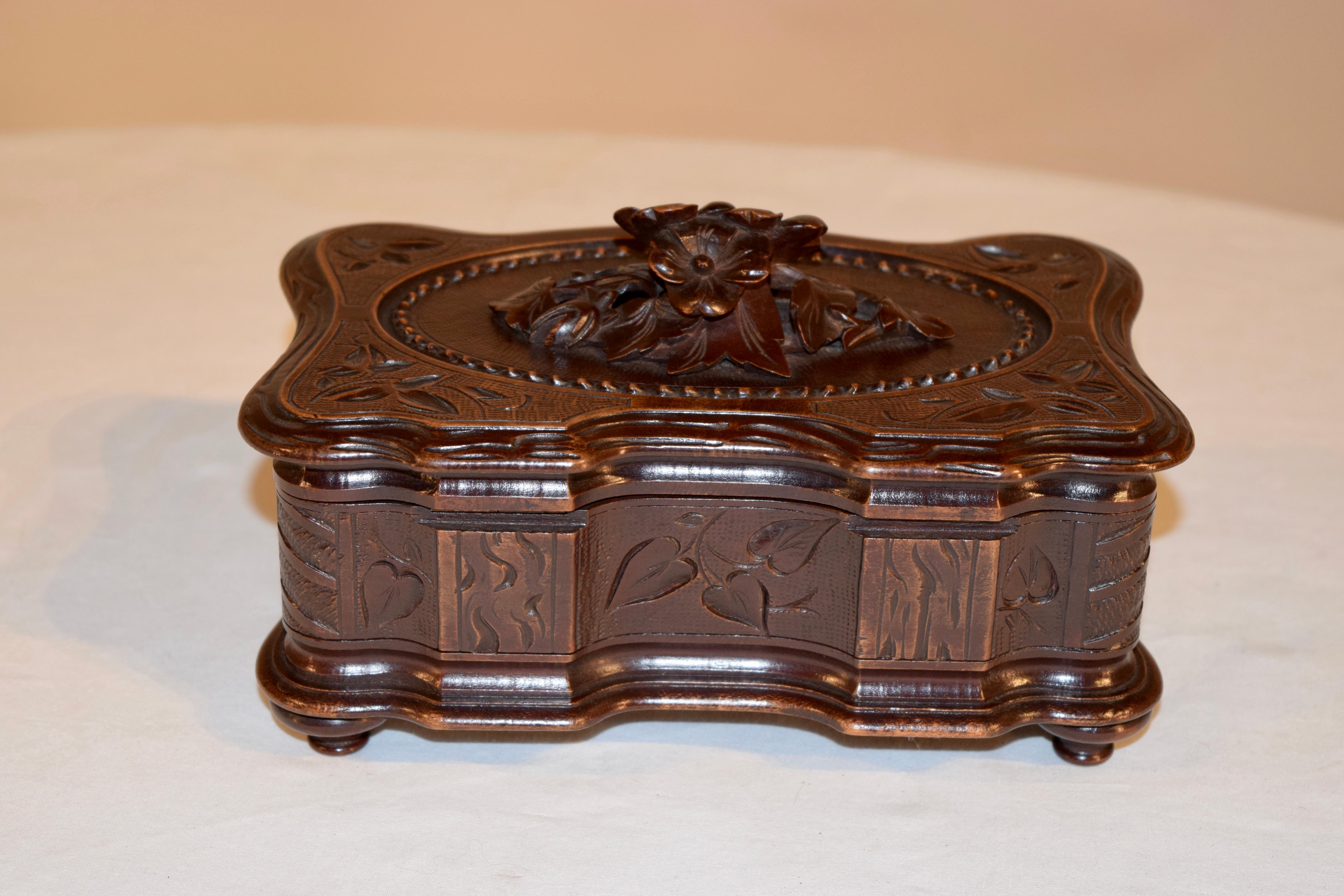 19th century hand carved jewelry box from the Black Forest region of Europe. The box has a mound of flowers carved on the top, surrounded by a hand carved and decorated surround on the lid and hand bevelled edge, which is also serpentined. The lid