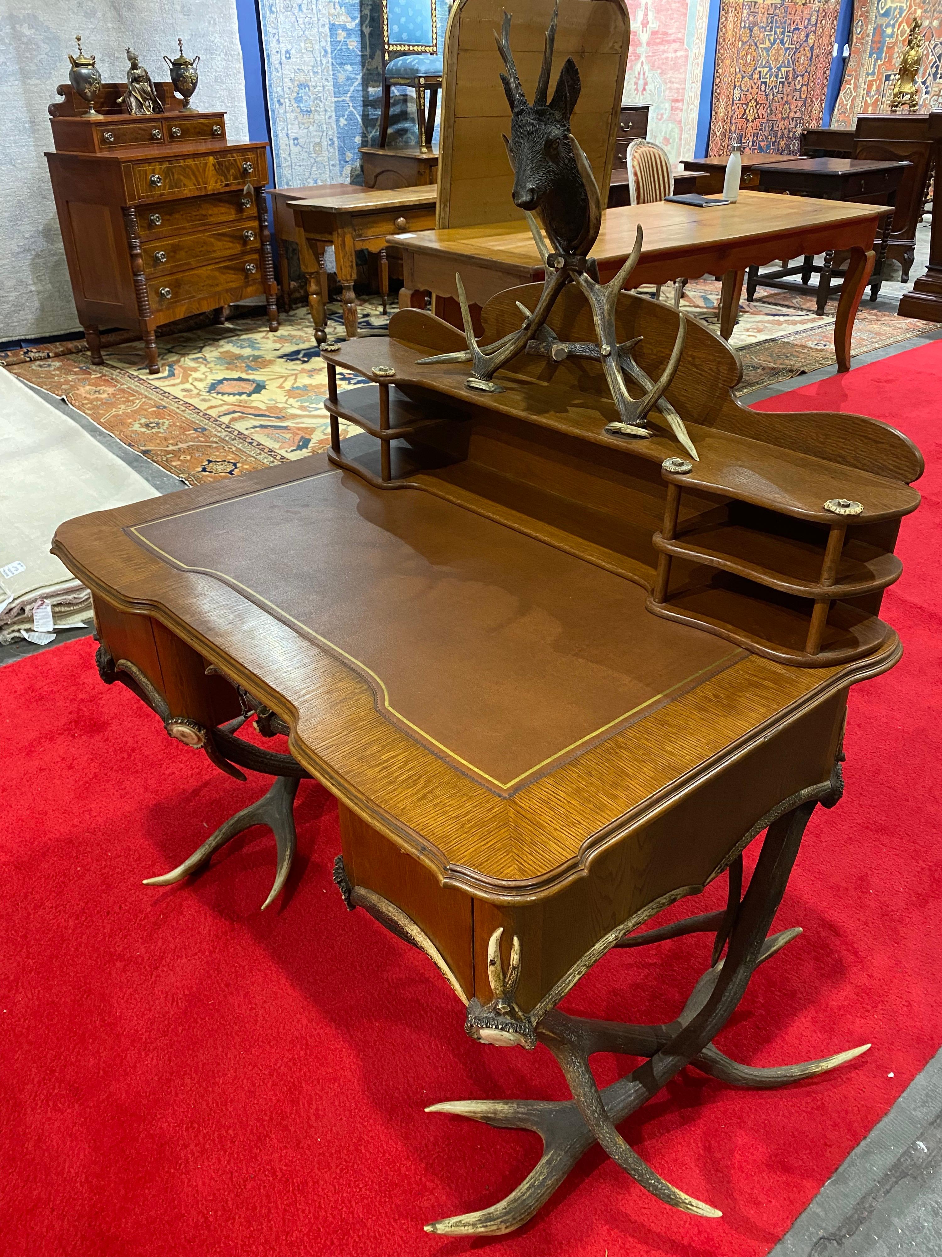 Impressive 19th century Black Forest leather top antler desk and removable shelf with a stags head. Desk is finished all around and can float in the center of the room. The shelf is meant to be hung on the wall but looks nice resting on the desk as