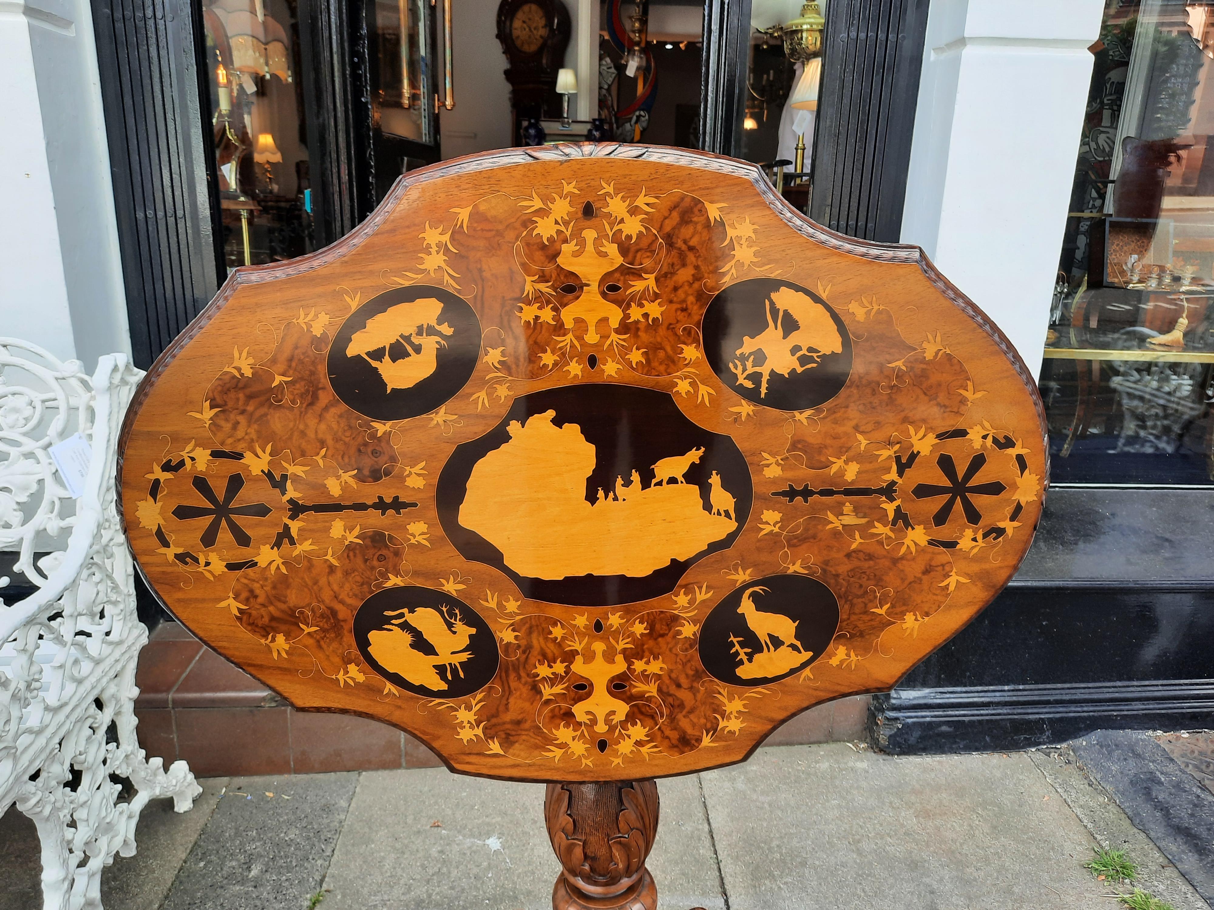 19th Century Black Forest Linden and Marquetry Inlaid Occasional Table, the shaped oval top decorated panels of Ibex, Chamois and Montain Deer landscapes above a pierced foliate frieze on carved acanthus column and tripod support - Swiss Gand Tour