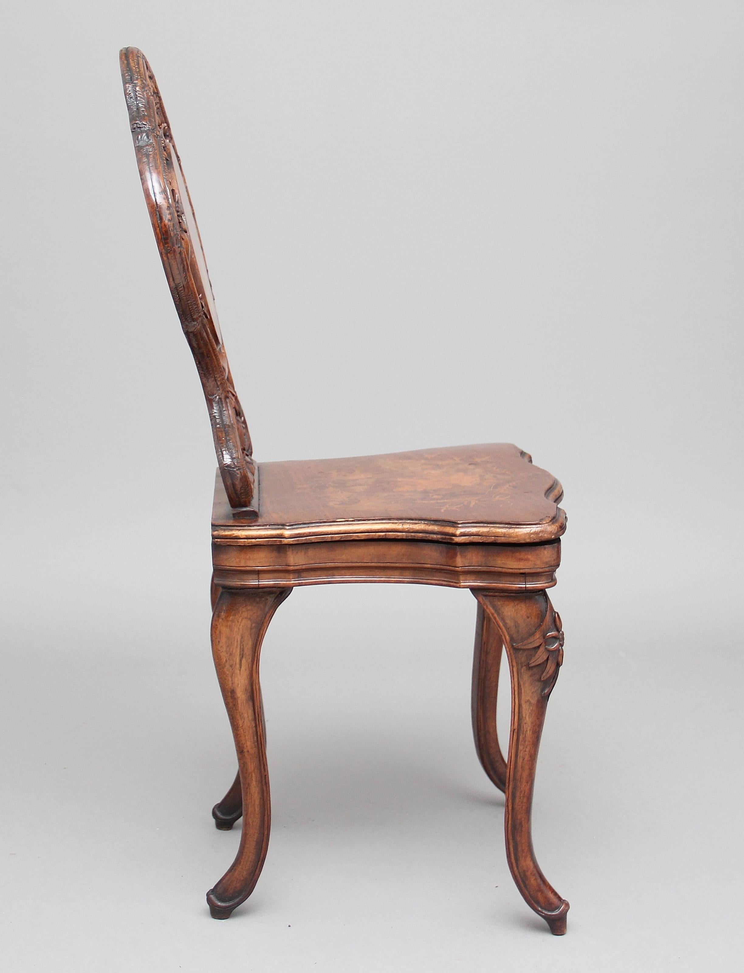 19th century Black Forest musical chair in walnut, the profusely carved back with an inlaid central panel and also an inlaid panel on the seat, depicting typical Swiss scenes, standing on four carved swept legs, circa 1890.
 