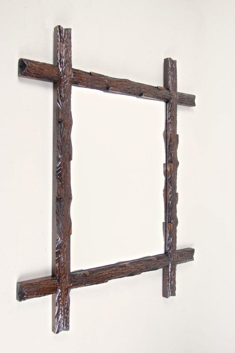 Estupendo espejo de pared rústico de madera de nuestra colección de espejos Black Forest de gran demanda. De Austria, circa 1880, nos llega este singular marco tallado a mano con esquinas salientes, que impresiona por su diseño rural de la 