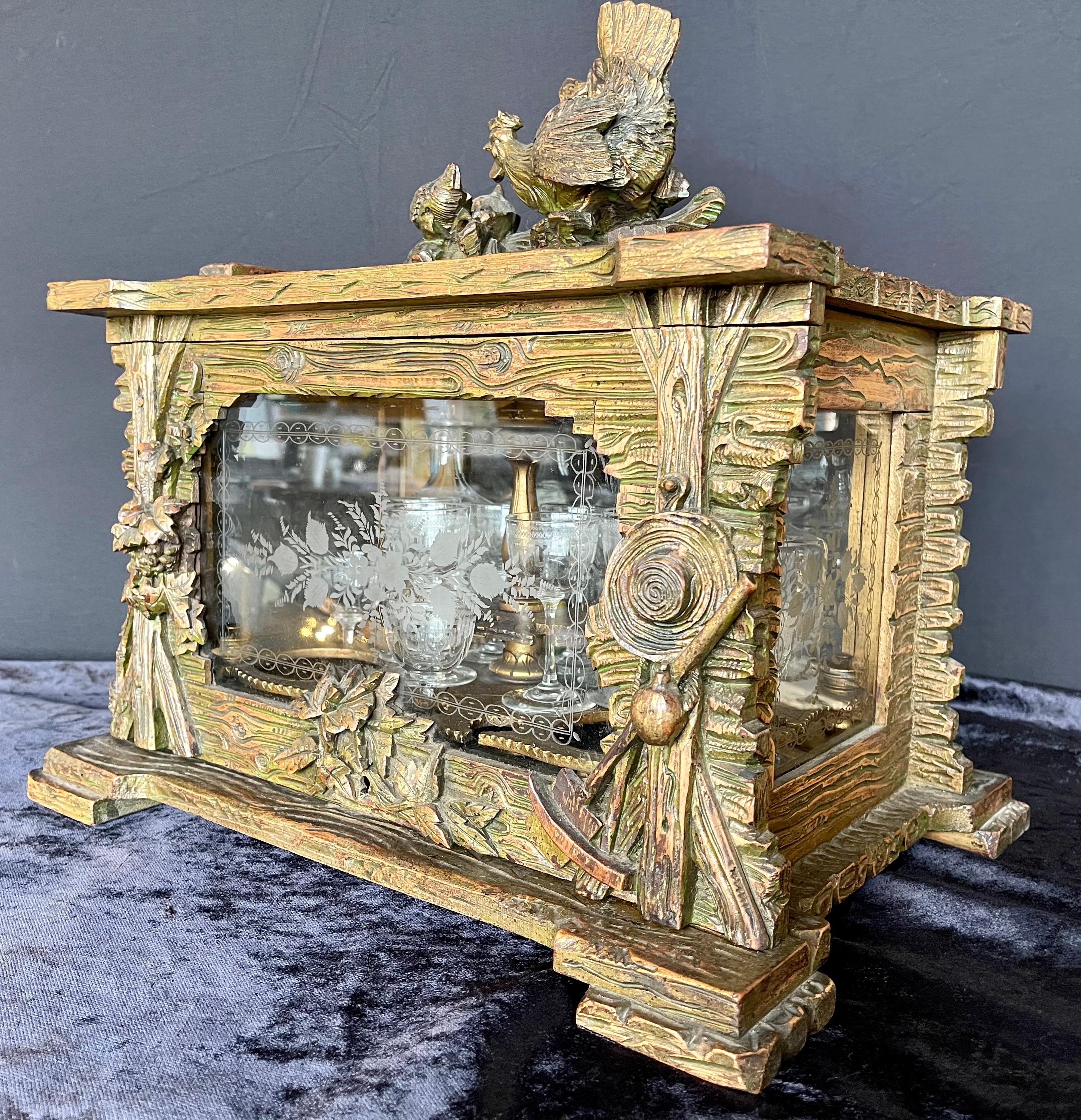 Antique Black Forest Tantalus. Carved wood with chicken and chicks finial, interesting side carvings, in the form of a wood shed/cabin. Etched glass 4 sides, only 2 decanters with stoppers. A stunning log cabin with spectacular carvings and a set of