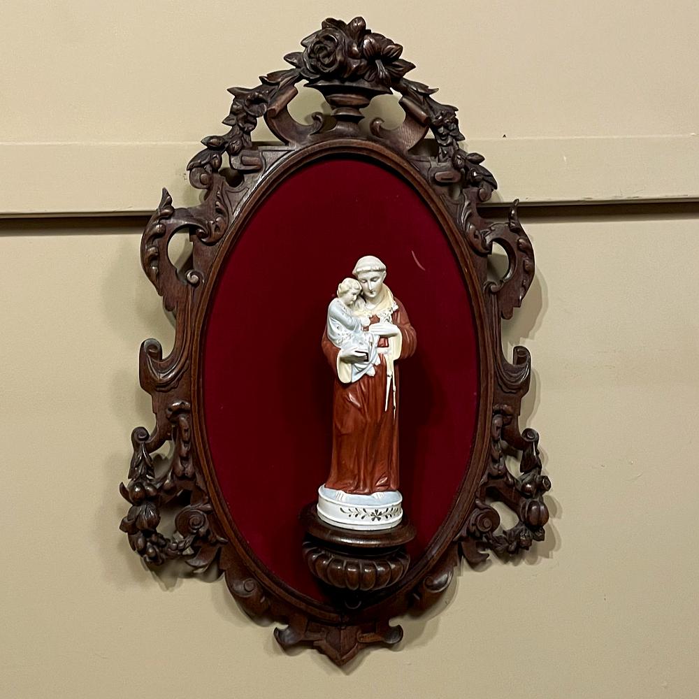 19th Century Black Forest Wall Shrine with Porcelain St. Anthony of Padua & Jesus will make a splendid devotional for any room, and features sculpted wood combining the Renaissance and Classical styles in a lovely oval form upon which has been