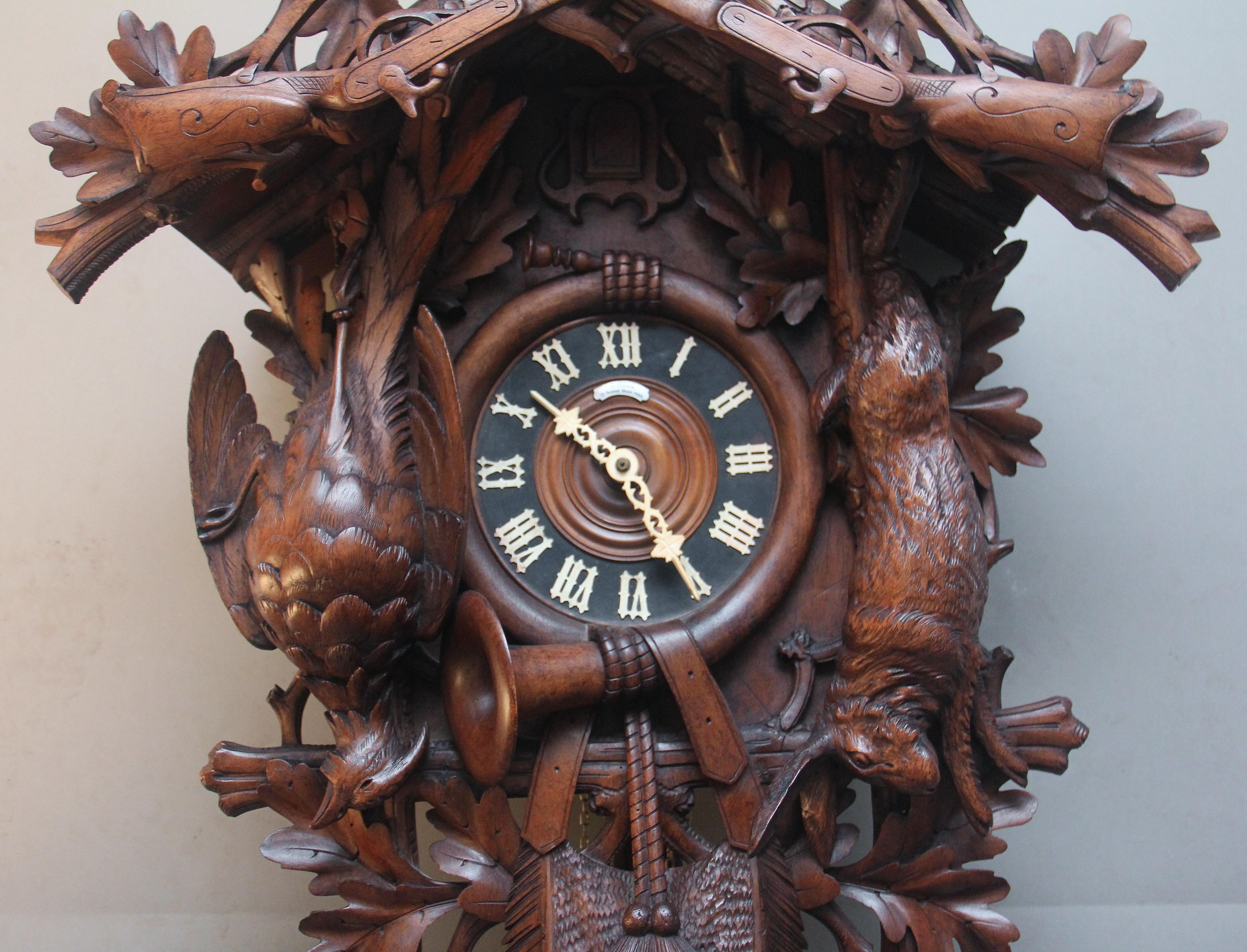 A superb quality 19th Century black forest carved walnut cuckoo clock with a 30 hour movement, the clock portraying a hunting scene consisting of a dears head at the top with antlers with various foliage either side, a couple of rifles hanging on