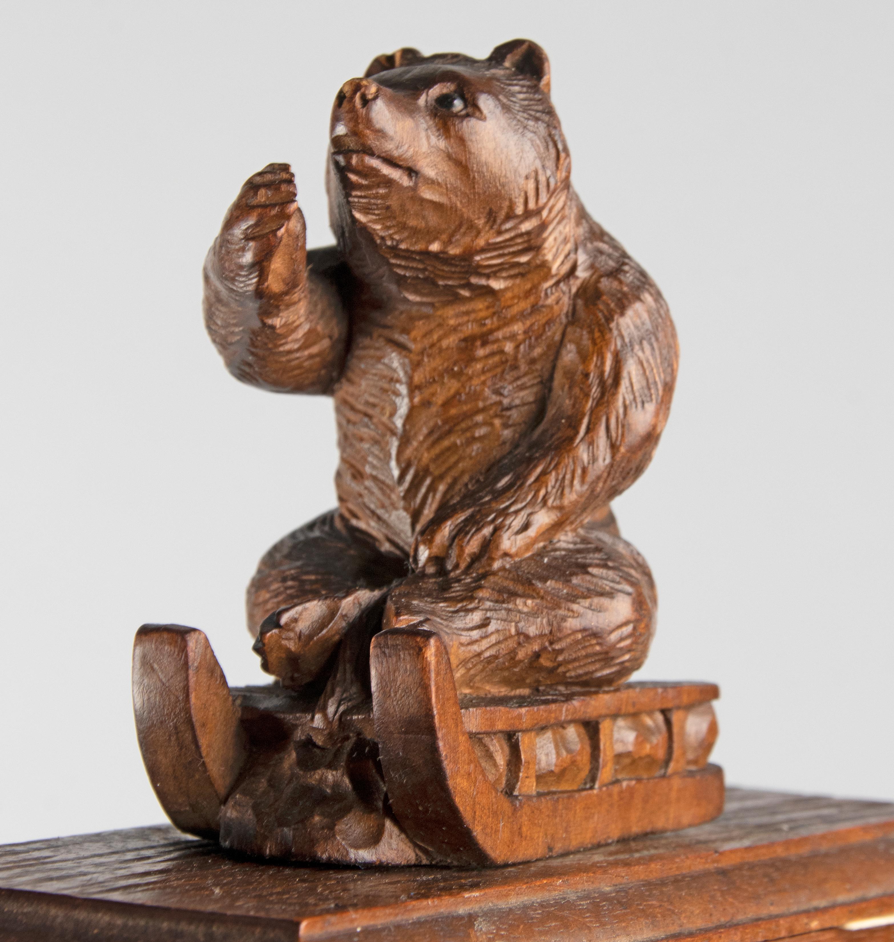 A finely antique sculpted desk blotter made from walnut wood. With a bear on a sled as handle, on a demi lune base. A typical Black Forest scene, where bears are more often a main subject in the Black forest theme, often depicted in a funny way. The