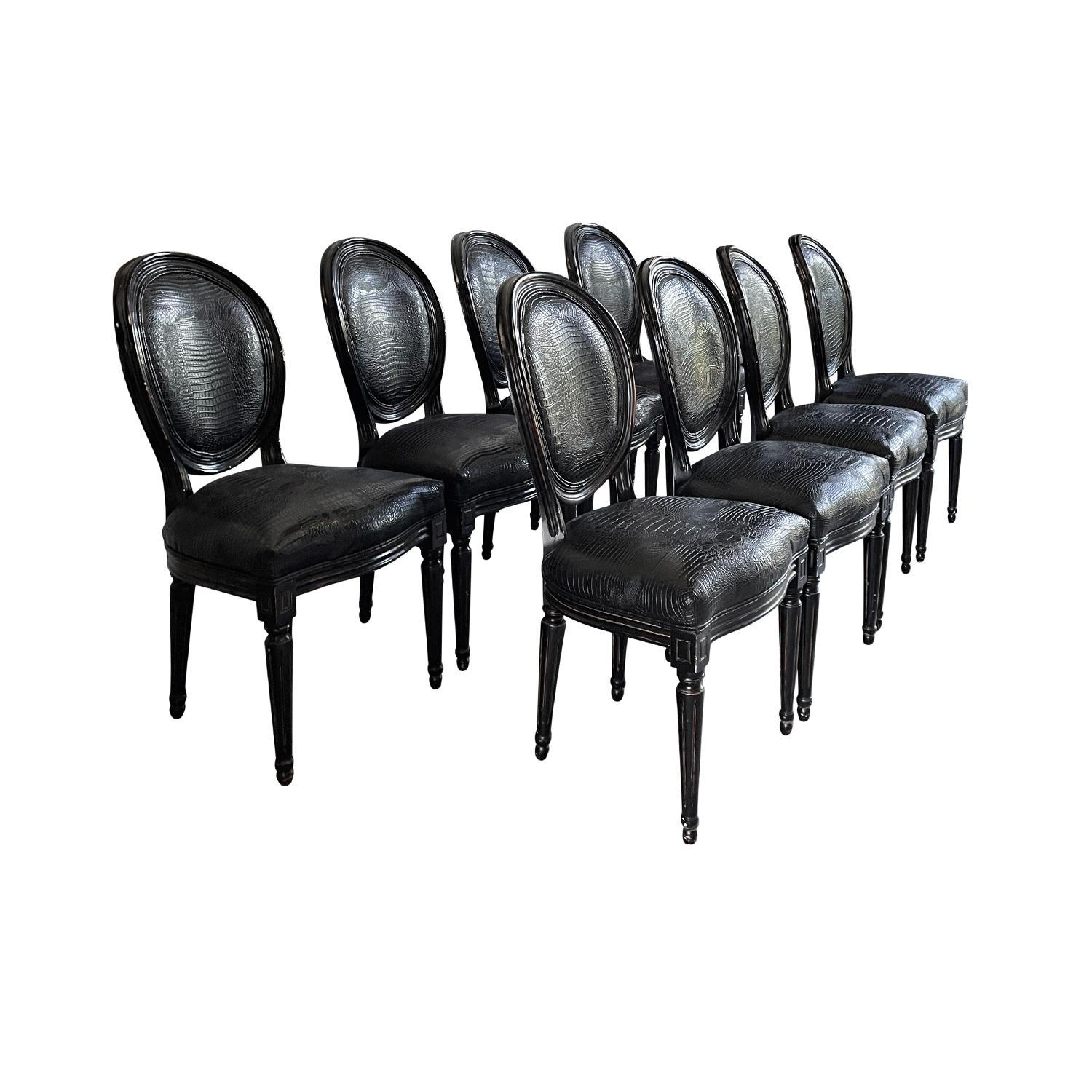 An antique French set of eight Louis XVI style Cabriolet side chairs with medallions lacquered in black Walnut and upholstered in a faux leather with crocodile pattern. The dining room chairs are in good condition. Wear consistent with age and use.