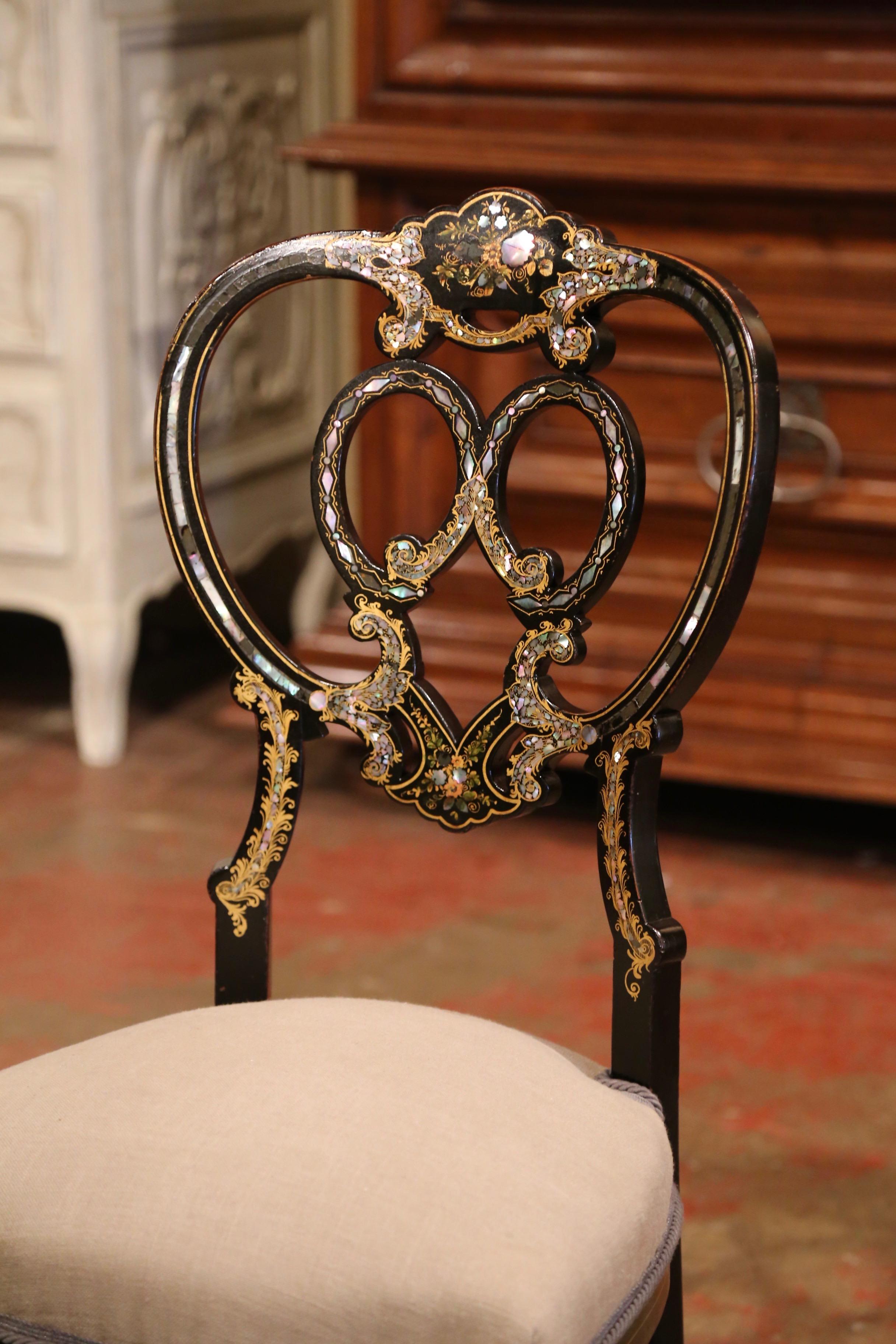 This elegant and colorful antique chair was crafted in France, circa 1870. The petite chair frame stands on four curved legs over a bombe scalloped apron, and features an elaborate curved ladder back. The chair is decorated with a shiny, black