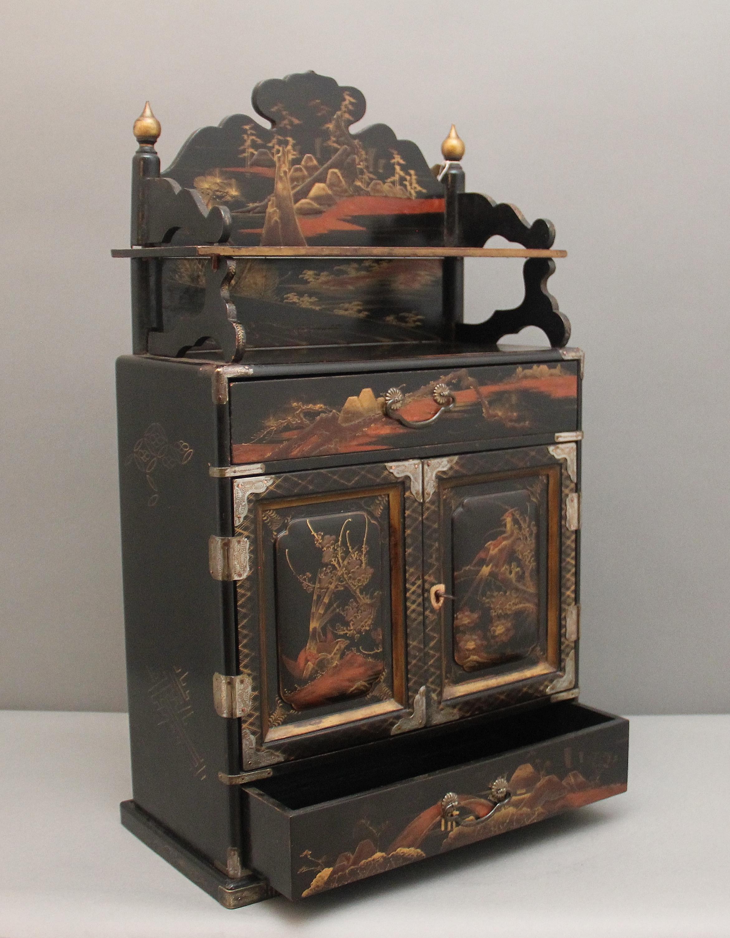 Mobile da tavolo indipendente giapponese del XIX secolo, laccato e dipinto di nero, risalente al periodo Meiji (1868-1912). La struttura superiore presenta uno schienale e un ripiano decorativo sagomato, mentre la sezione principale è composta da