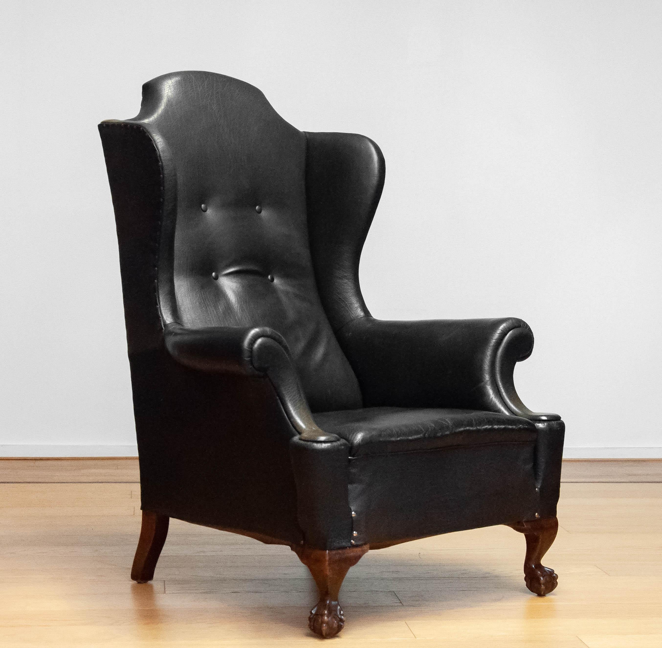 Highly decorative and large black leather 'Thomas Chappendale style' wingback chair from the end of the 19th century. During his live pieces of leather has been replaced what gives this chair a beautiful character and therefor a absolute eye