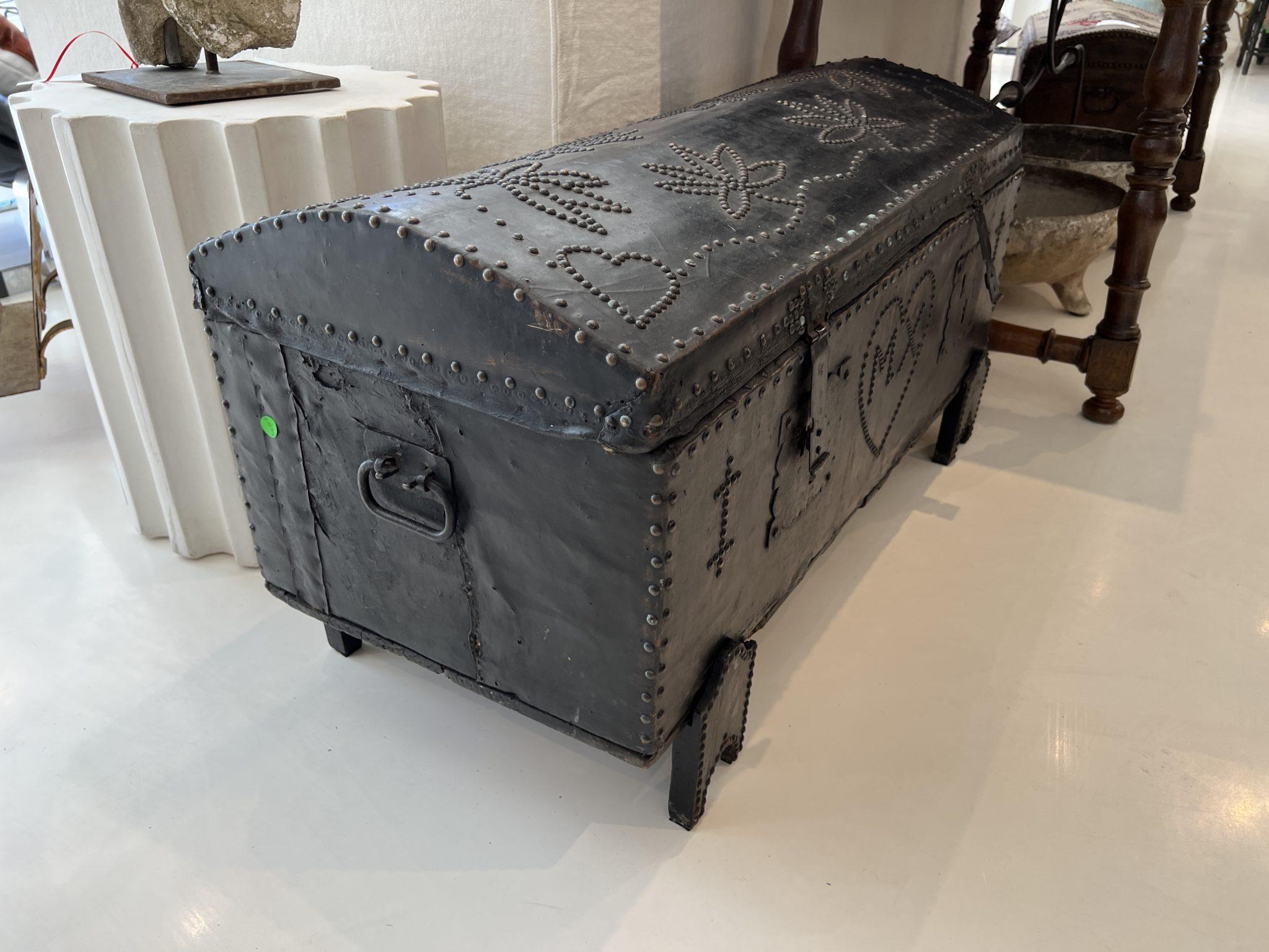 Black leather trunk with nailhead decoration in the shapes of hearts and flowers. Also has monogram of MX in a heart in front.