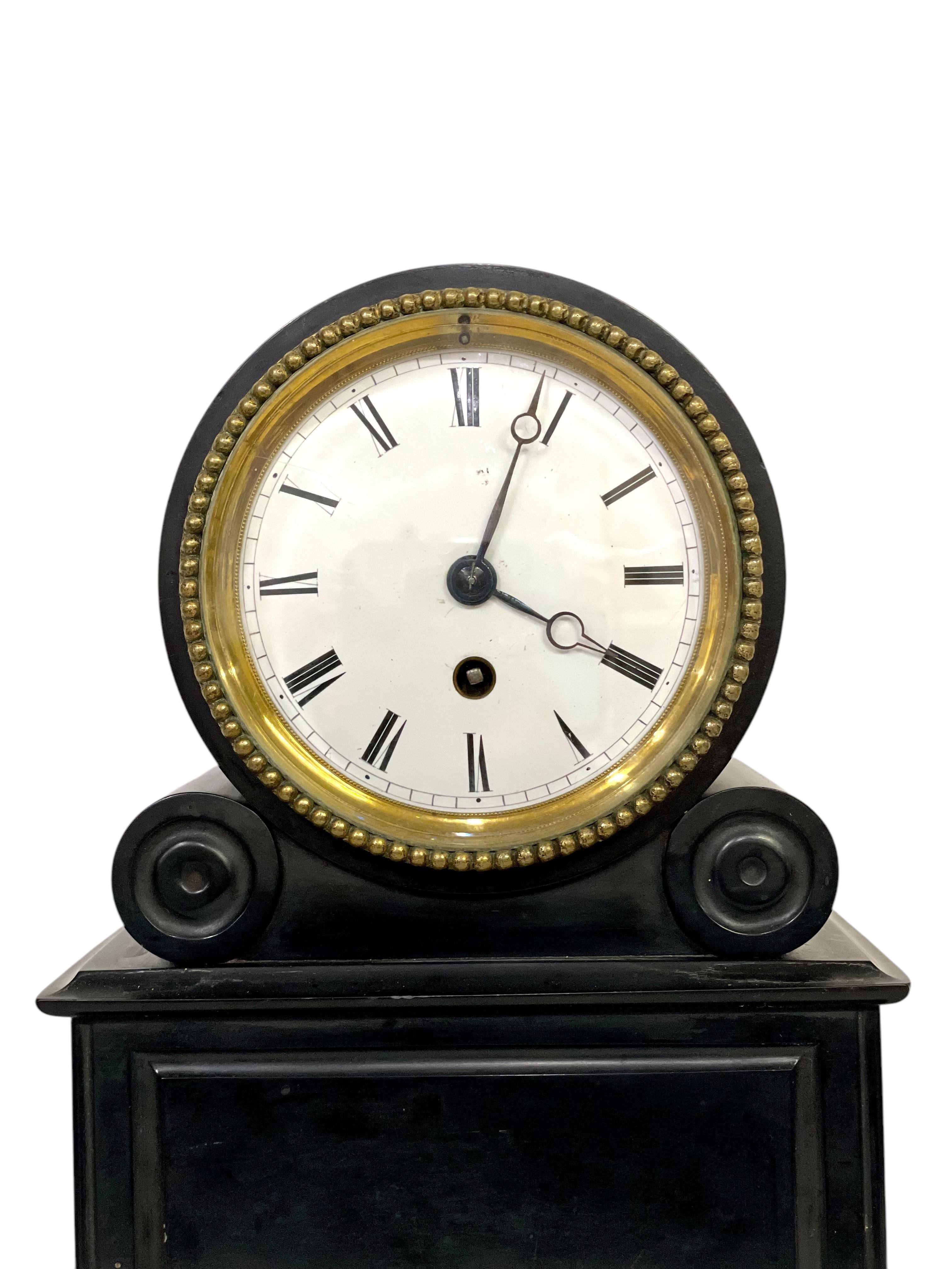 This elegant antique French mantel clock is crafted from exquisite black marble, showcasing timeless sophistication and 19th-century charm. The clock features a circular enamel dial with Roman numerals, surrounded by a decorative brass bezelwith a