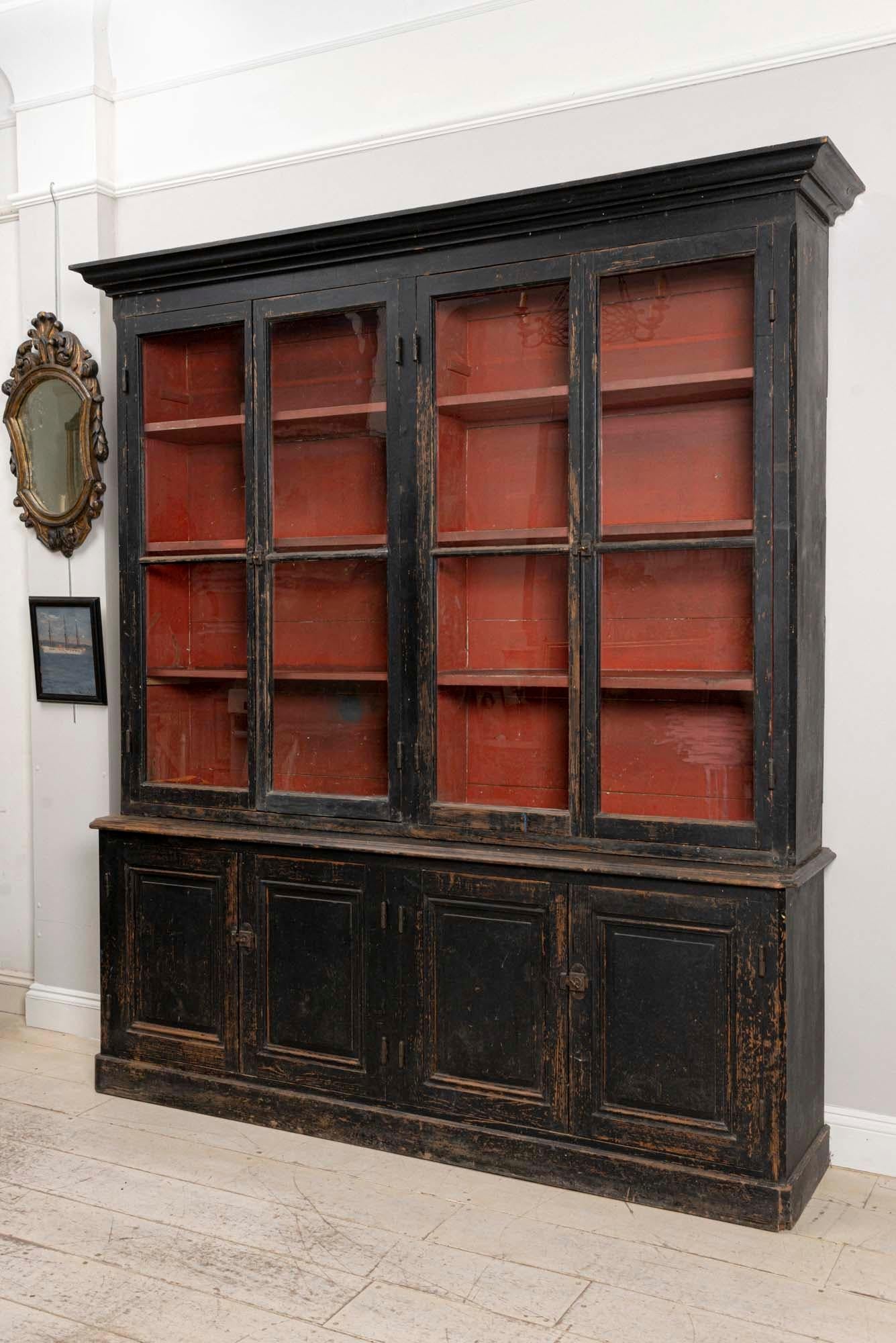 French black painted bookcase, in the 'moderne' style, circa 1890s.
The original exterior black paint was complimented later with a warm deep burgundy interior finish which sits behind four glazed doors.
The bookcase is of handsome slightly taller