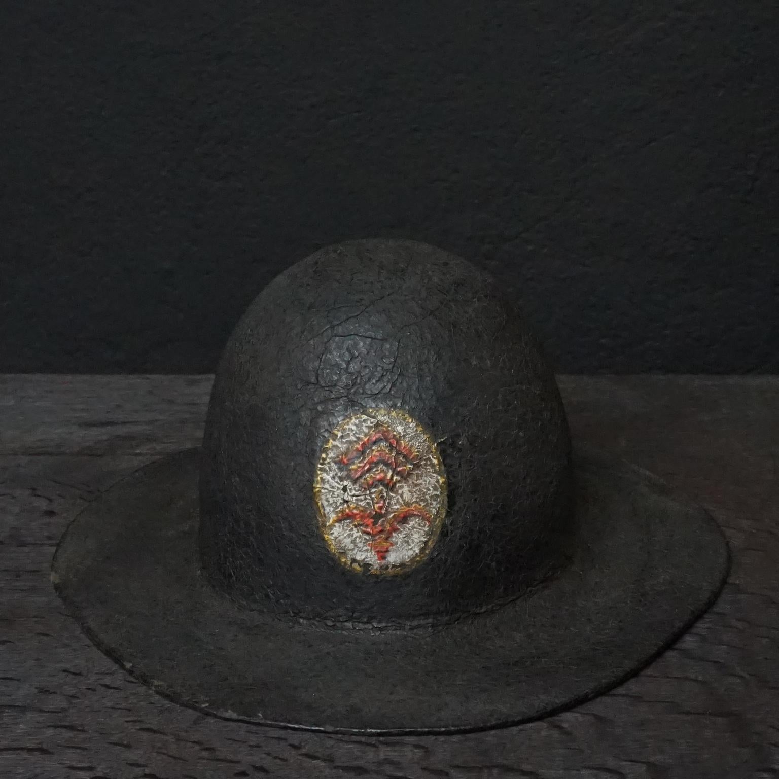 19th century black painted leather French fire helmet with painted logo with what looks like a 'French Lily' and three hooked lines
Made out of one piece of hardened and painted leather, soft leather lining held together by a (not original)
