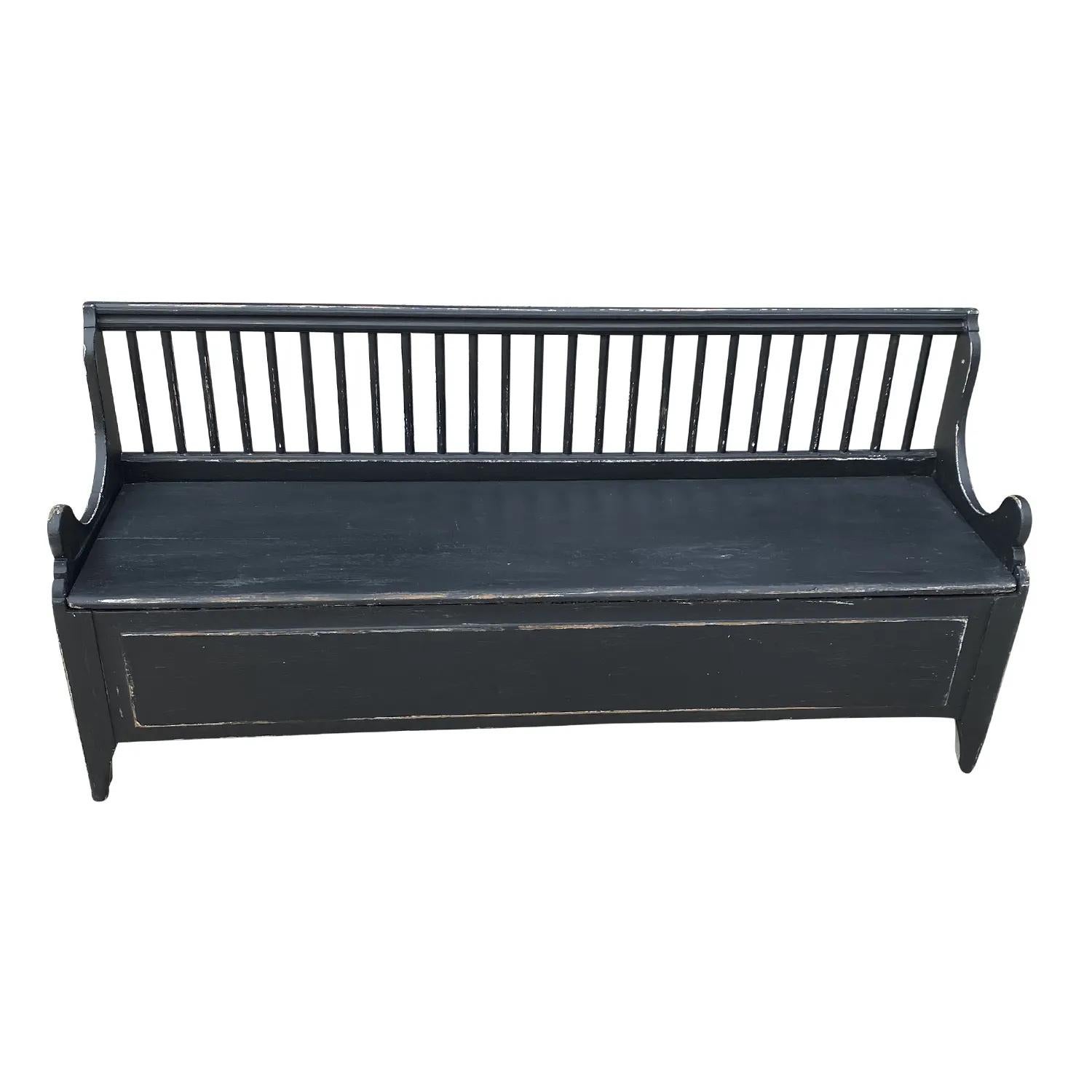A black, antique Swedish Gustavian FÅLLBÄNK, fall bench composed with a storage space below sitting area, made of hand crafted painted Pinewood, in good condition. The back rest of the Scandinavian wood bench is spindled with small, arched armrests,