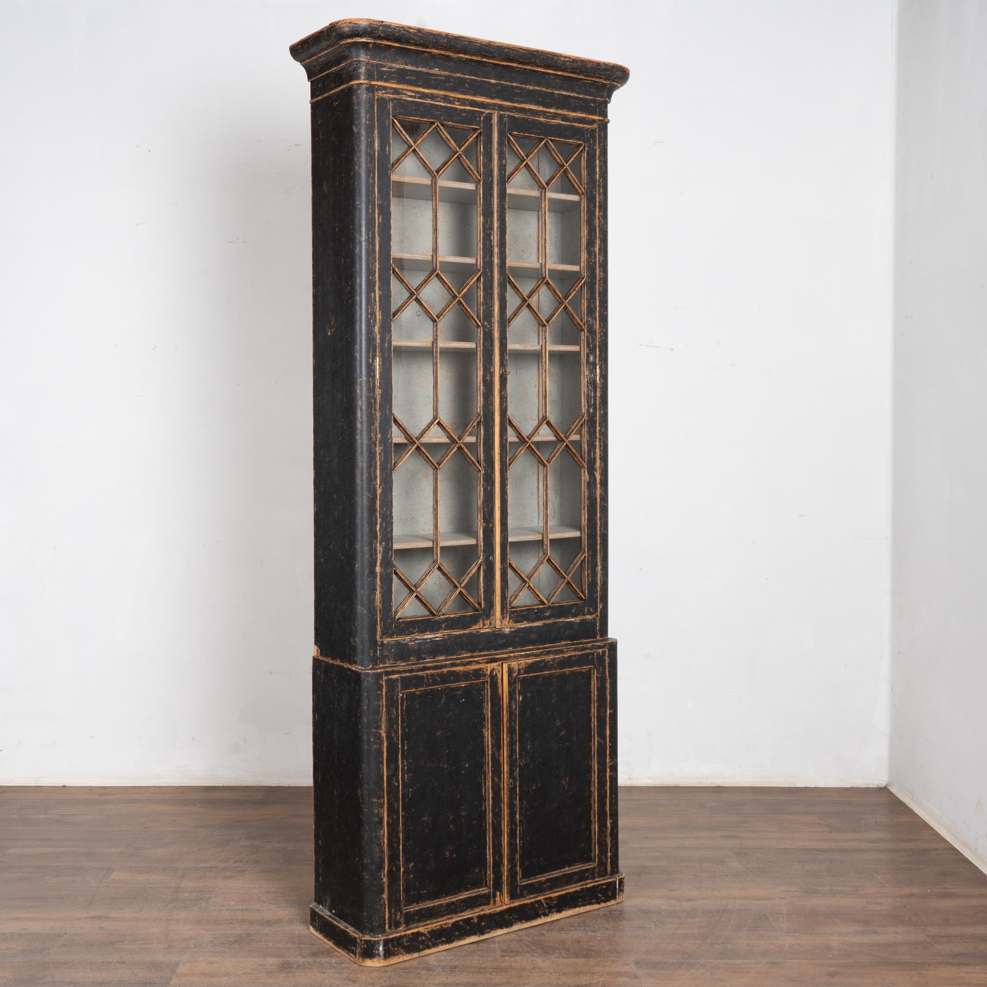 Schmale und hohe schwedische Vitrine mit dekorativem Gitterwerk entlang der oberen Glastüren. 
Beachten Sie die auffallend schwarz lackierte Außenseite und die kontrastierende graue Innenseite; obwohl es sich um ein neueres Finish handelt, ist es