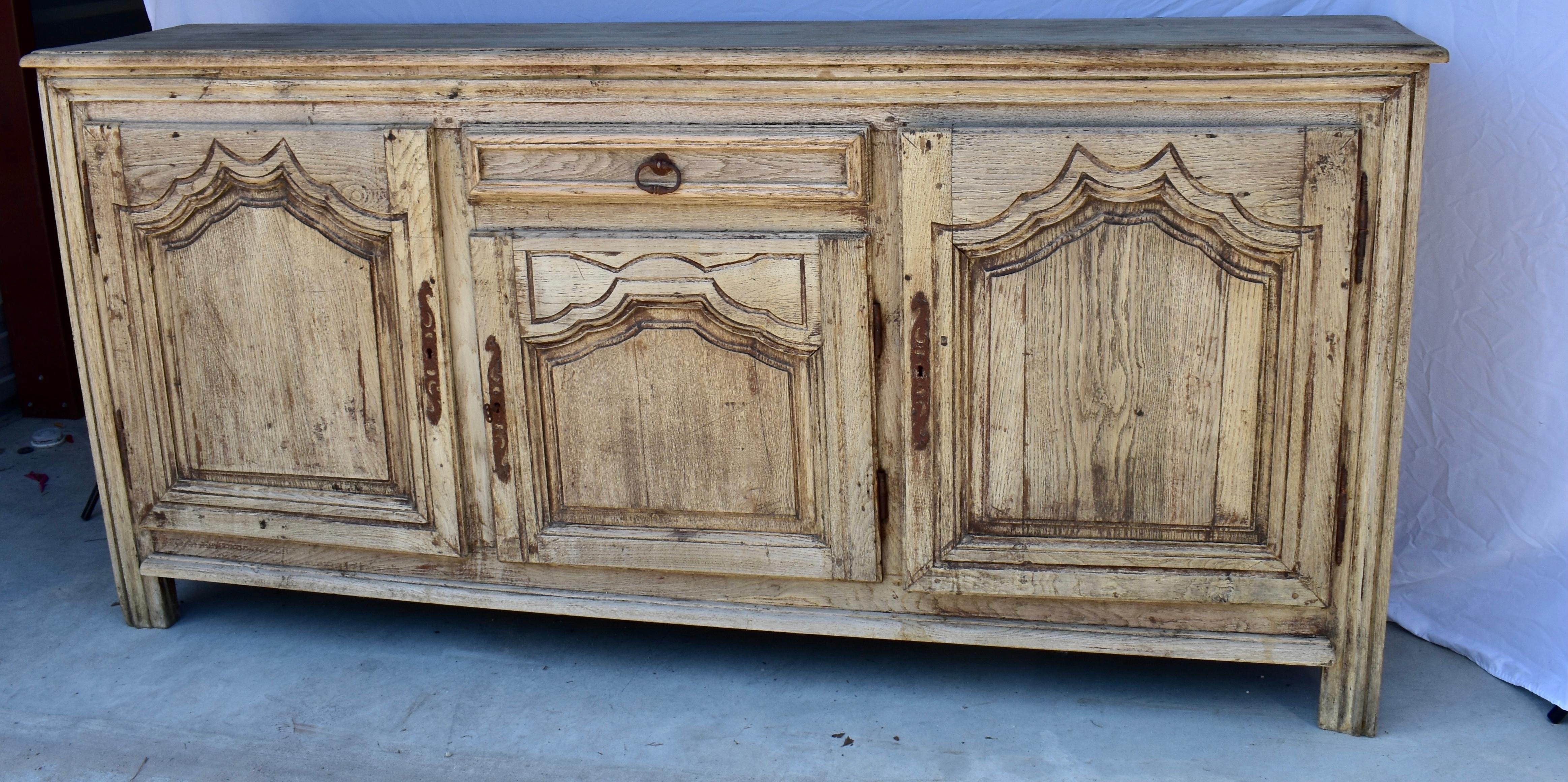 This is a gorgeous Louis XV buffet built in France in the early 1800s using oak and pegged construction. The buffet features three doors each composed of a chamfered panel framed by hand-carved molding, providing the piece with a lot of depth. The