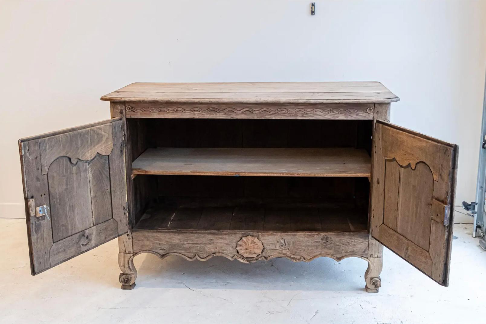 Elegantemente fabricado en el siglo XIX, este armario de dos puertas estilo Luis XV encarna la sofisticación francesa con su silueta graciosamente curvada, sus intrincados detalles tallados a mano y su acabado en roble blanqueado bellamente